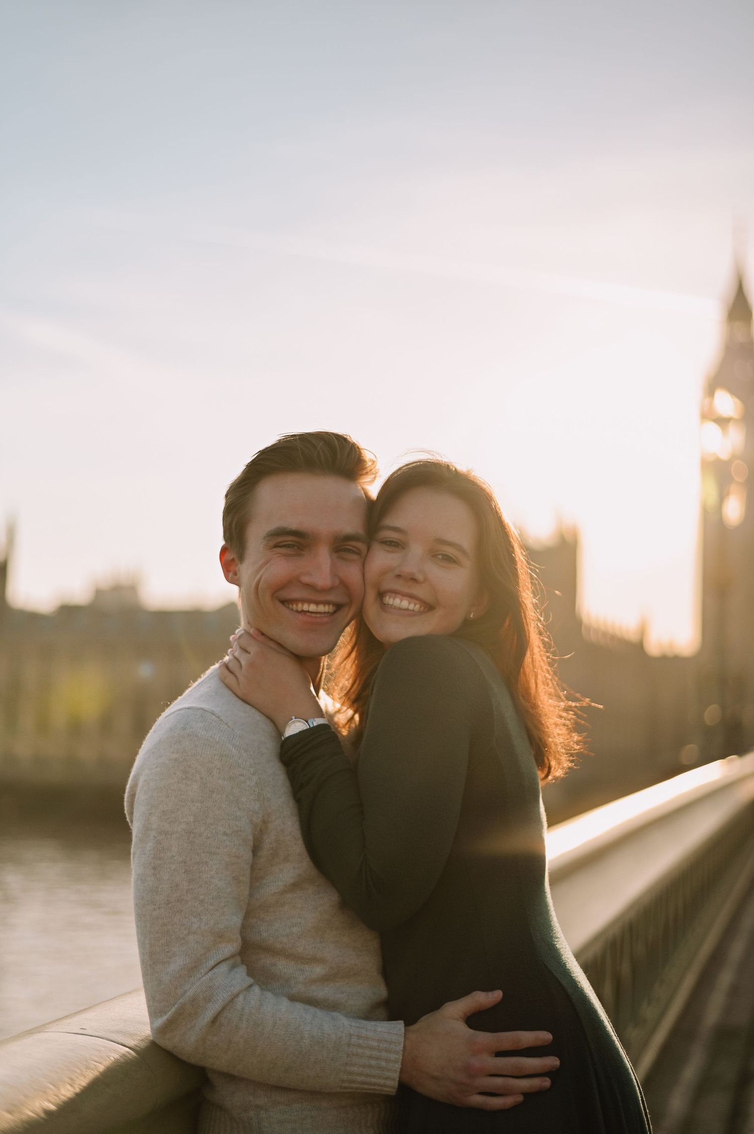 Smiling couple embracing on Westminster Bridge with Big Ben at golden hour in London.