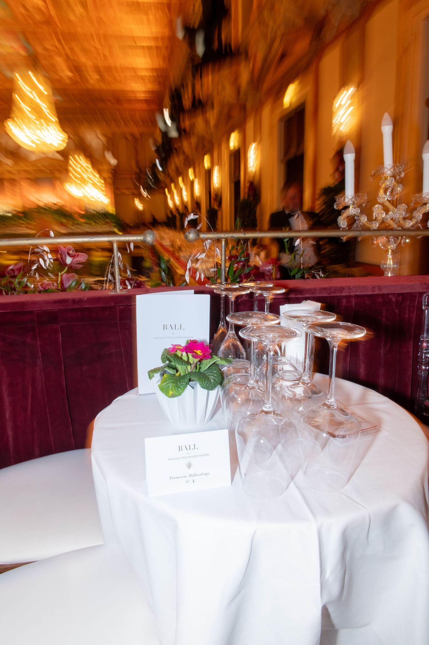 Elegant banquet table with crystal glasses, floral centerpiece, and menu cards in a luxurious ballroom setting.