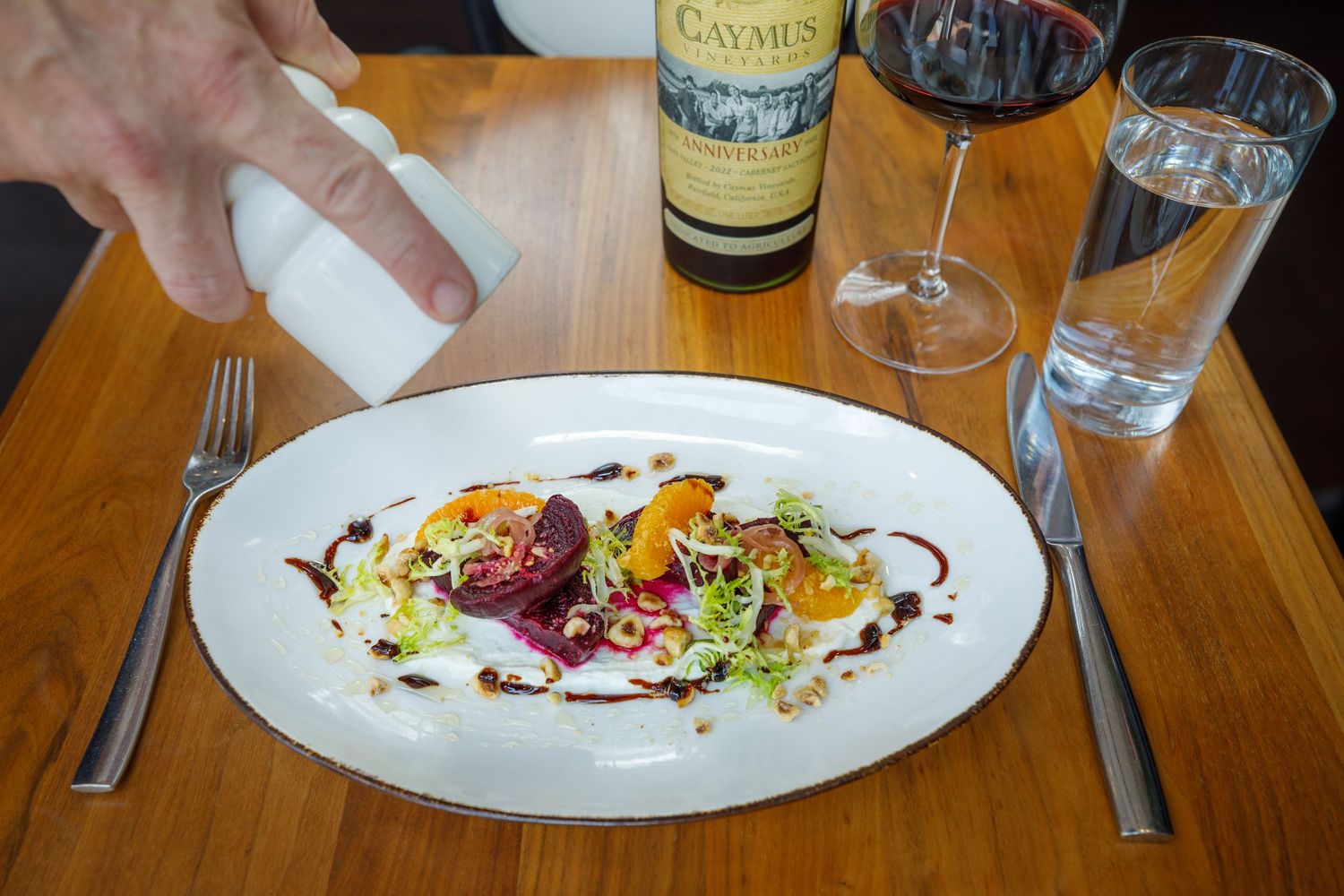 Fine dining experience with elegant plated dishes and wine glasses on a wooden table.