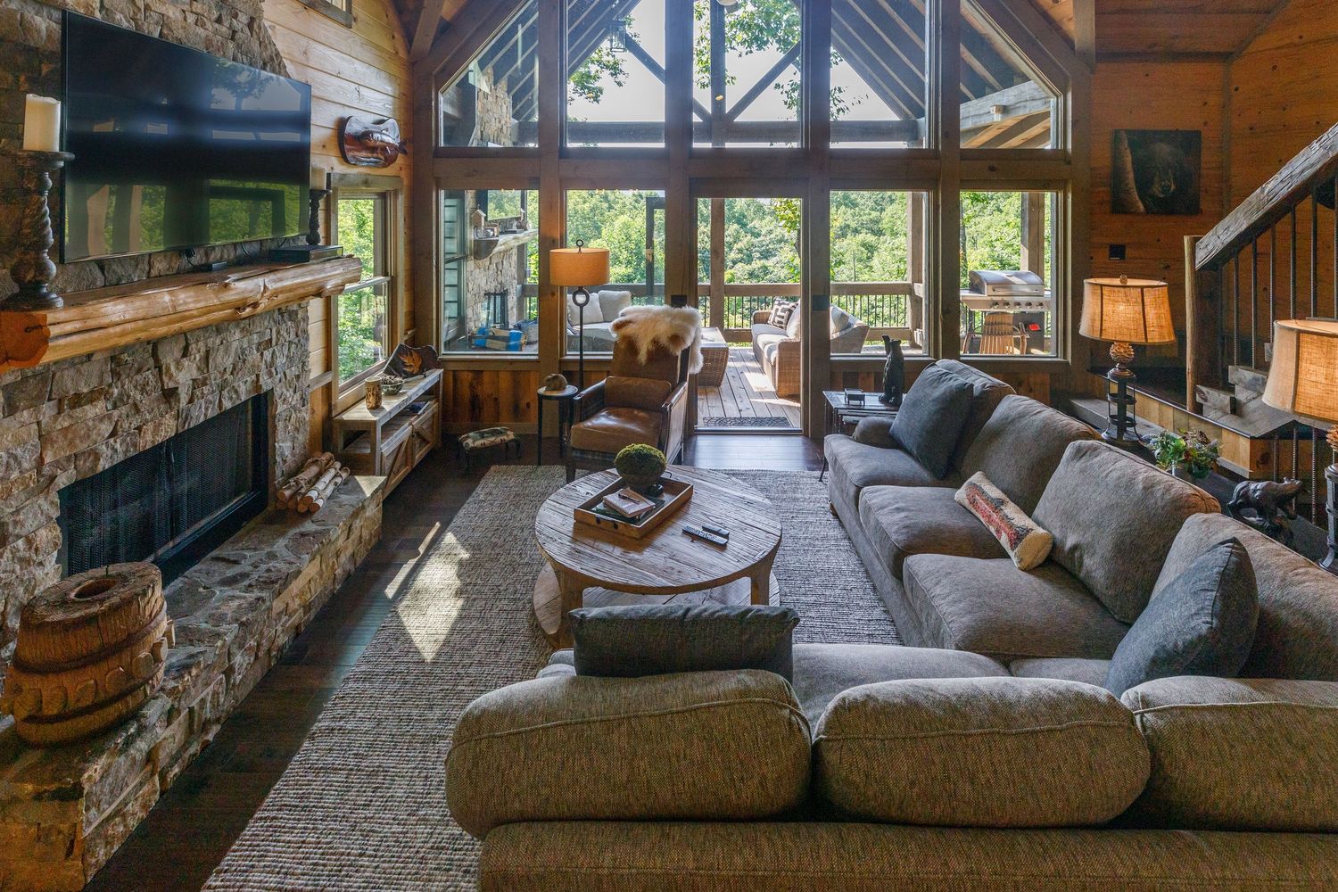 Luxurious mountain lodge living room with stone fireplace and panoramic windows.