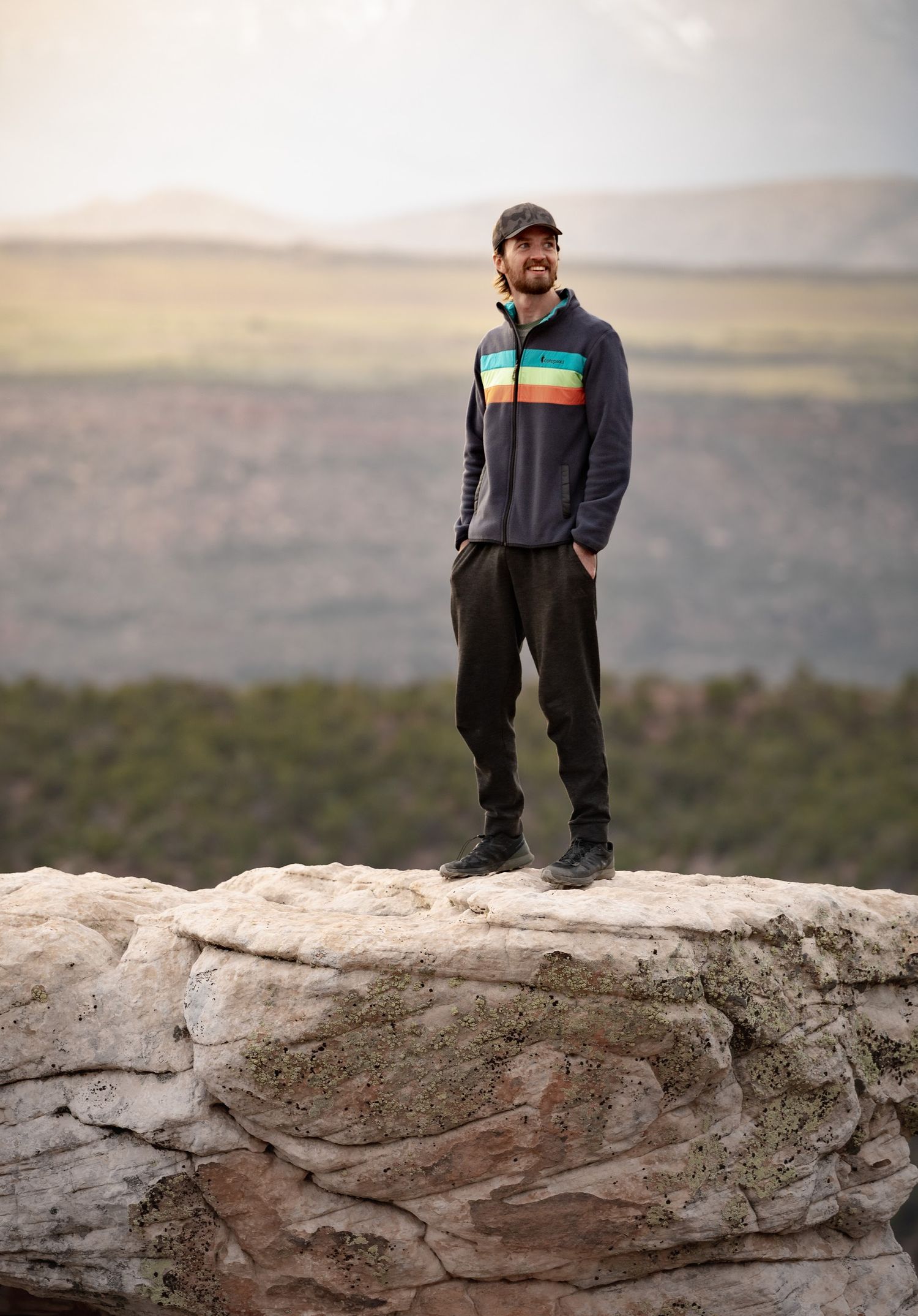 Person standing on rocky outcrop overlooking desert landscape in multiple sequential photos.