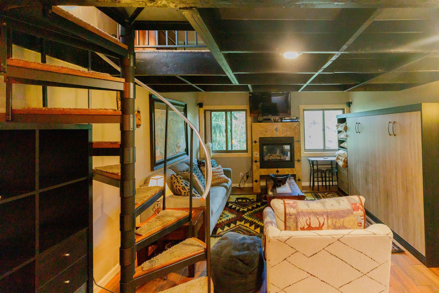 Spacious basement recreation room with dark ceiling and modern lighting fixtures.