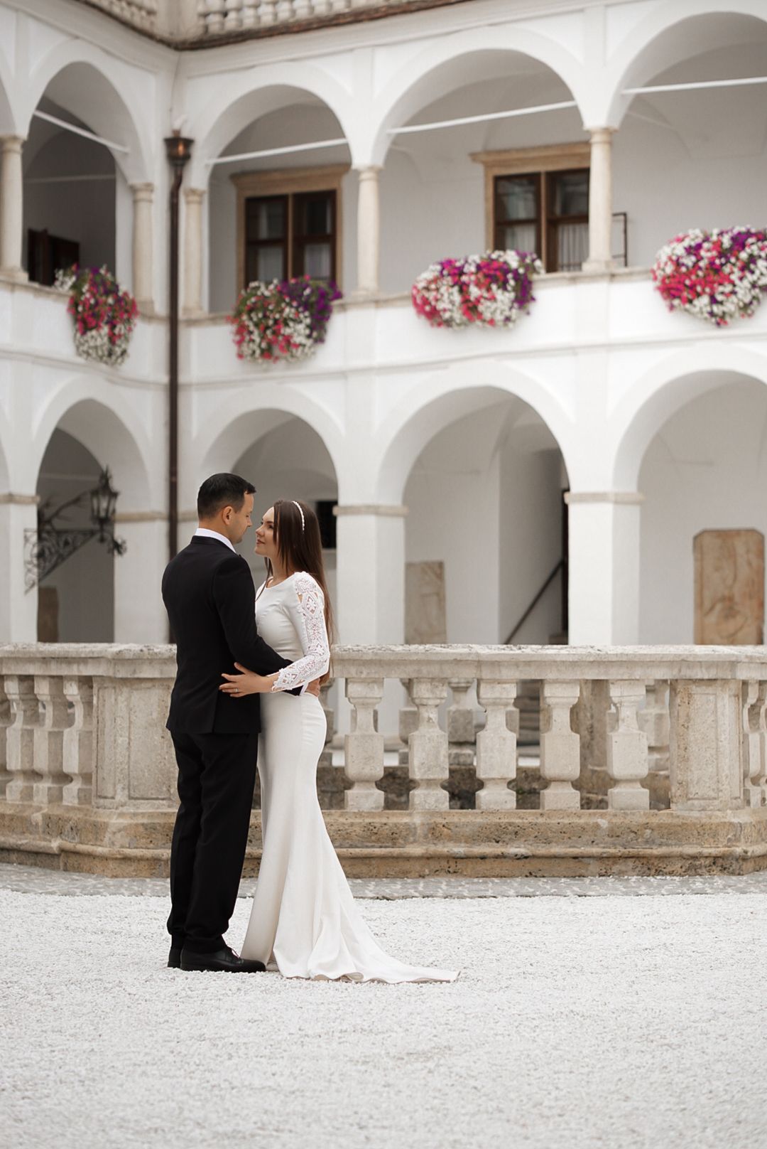 Wedding ceremony in a stunning courtyard with white arches and pink floral decorations.