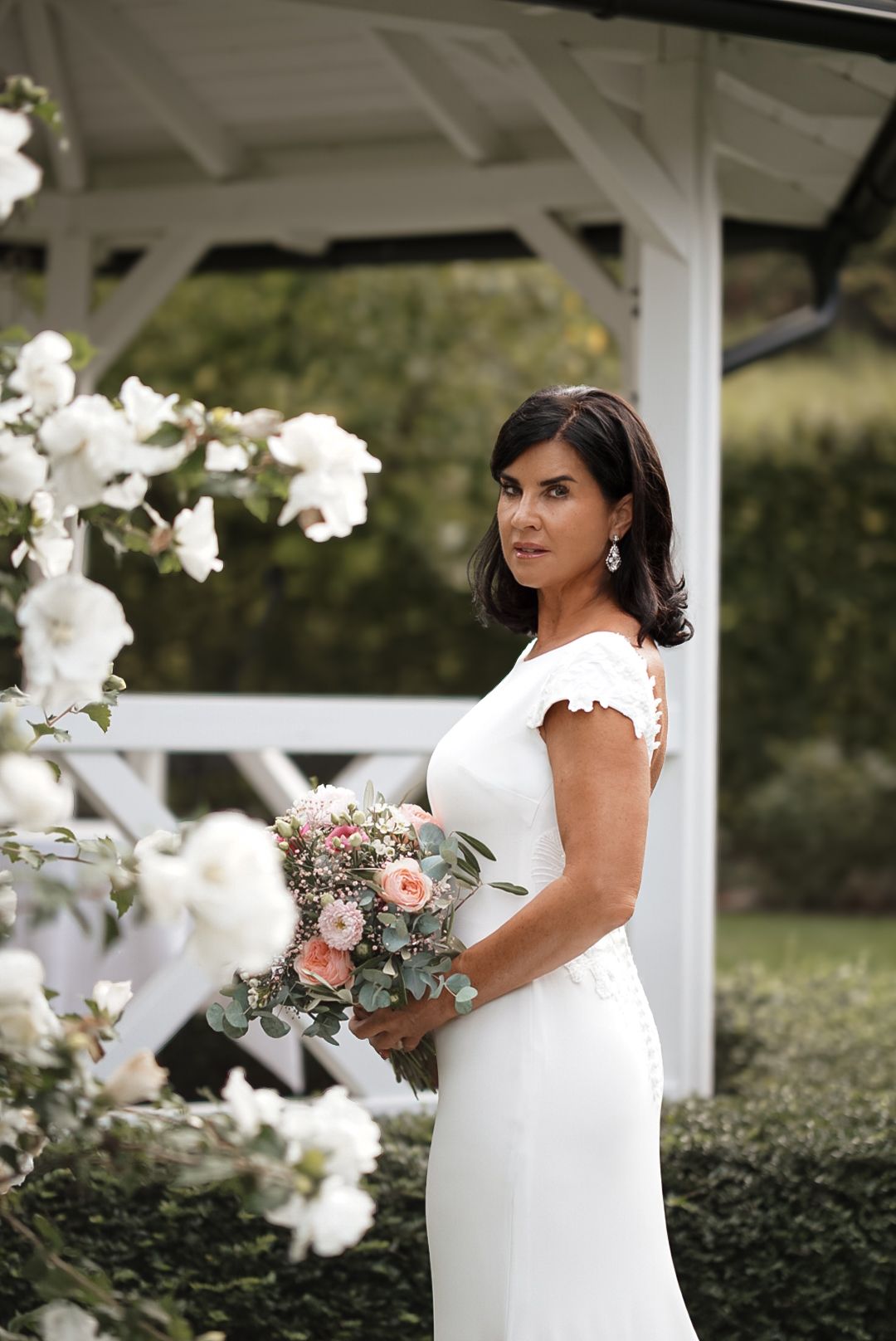 Elegant white wedding dress with delicate lace details and a beautiful peach and eucalyptus bouquet.