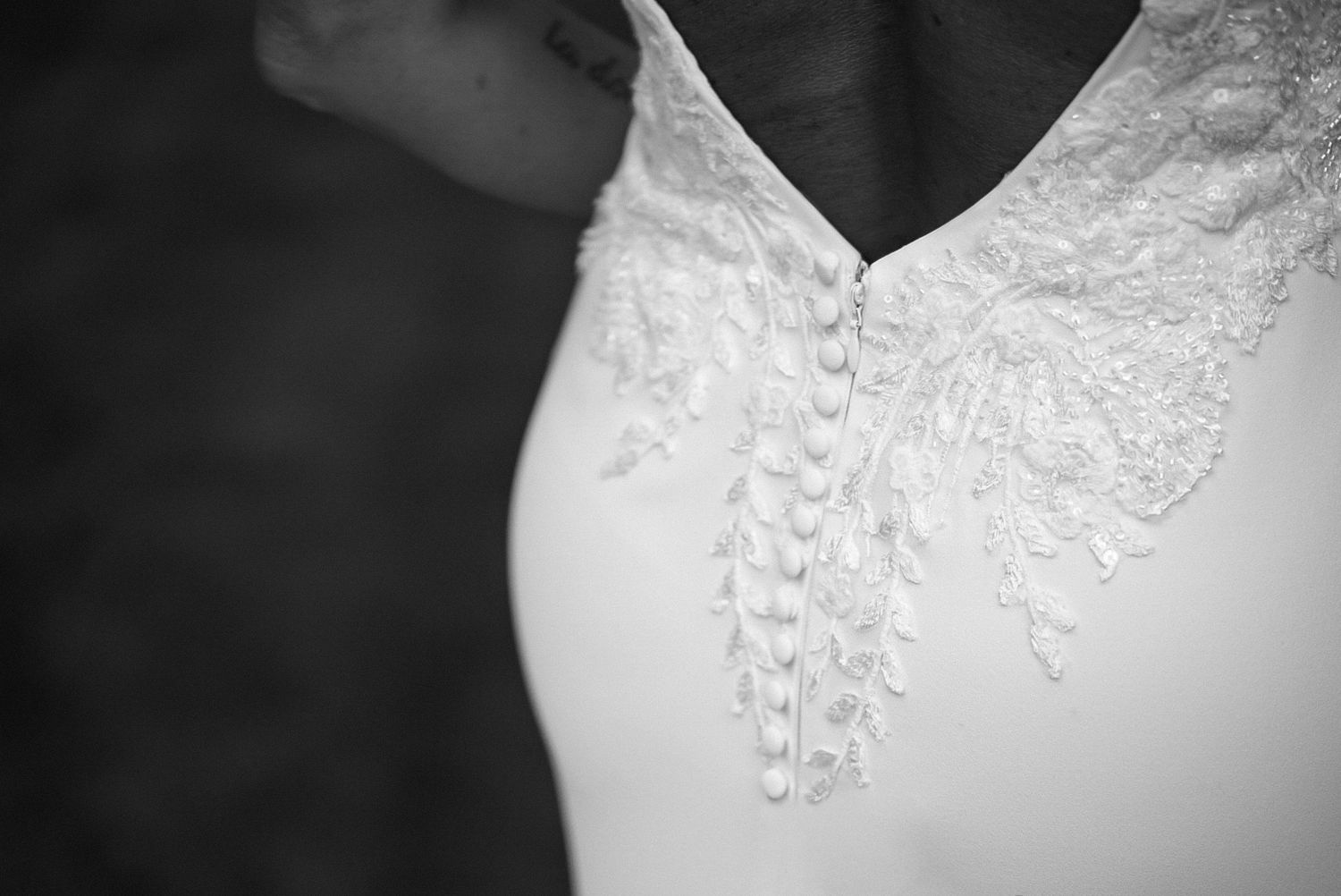 Close-up detail of delicate lace embellishments on a white wedding dress bodice.
