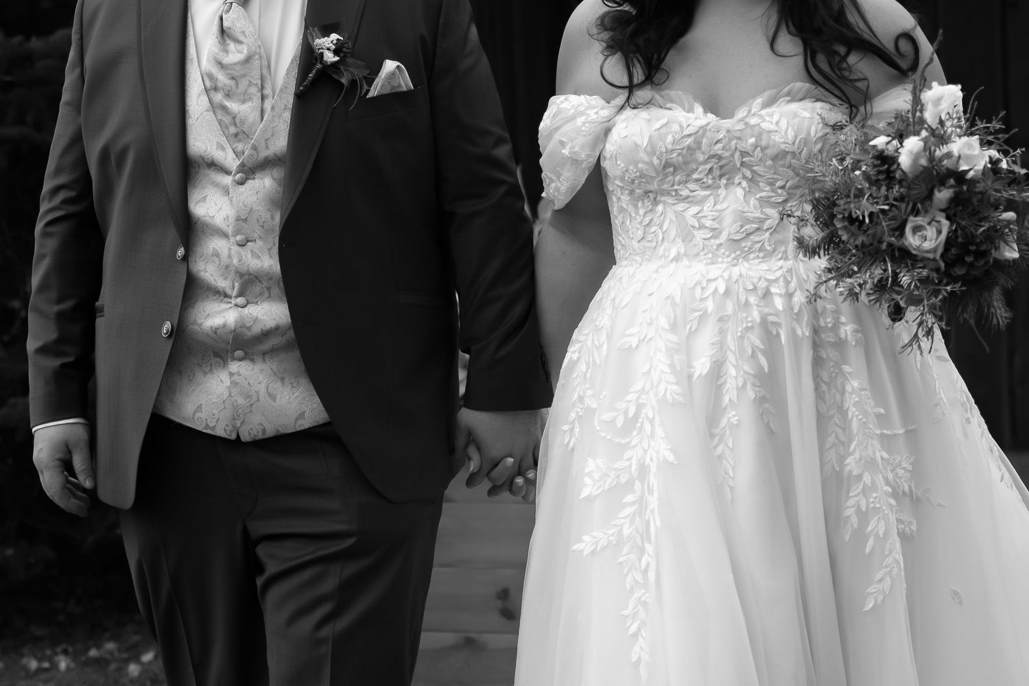 A formal wedding portrait showing elegant white lace dress details and dark suit.