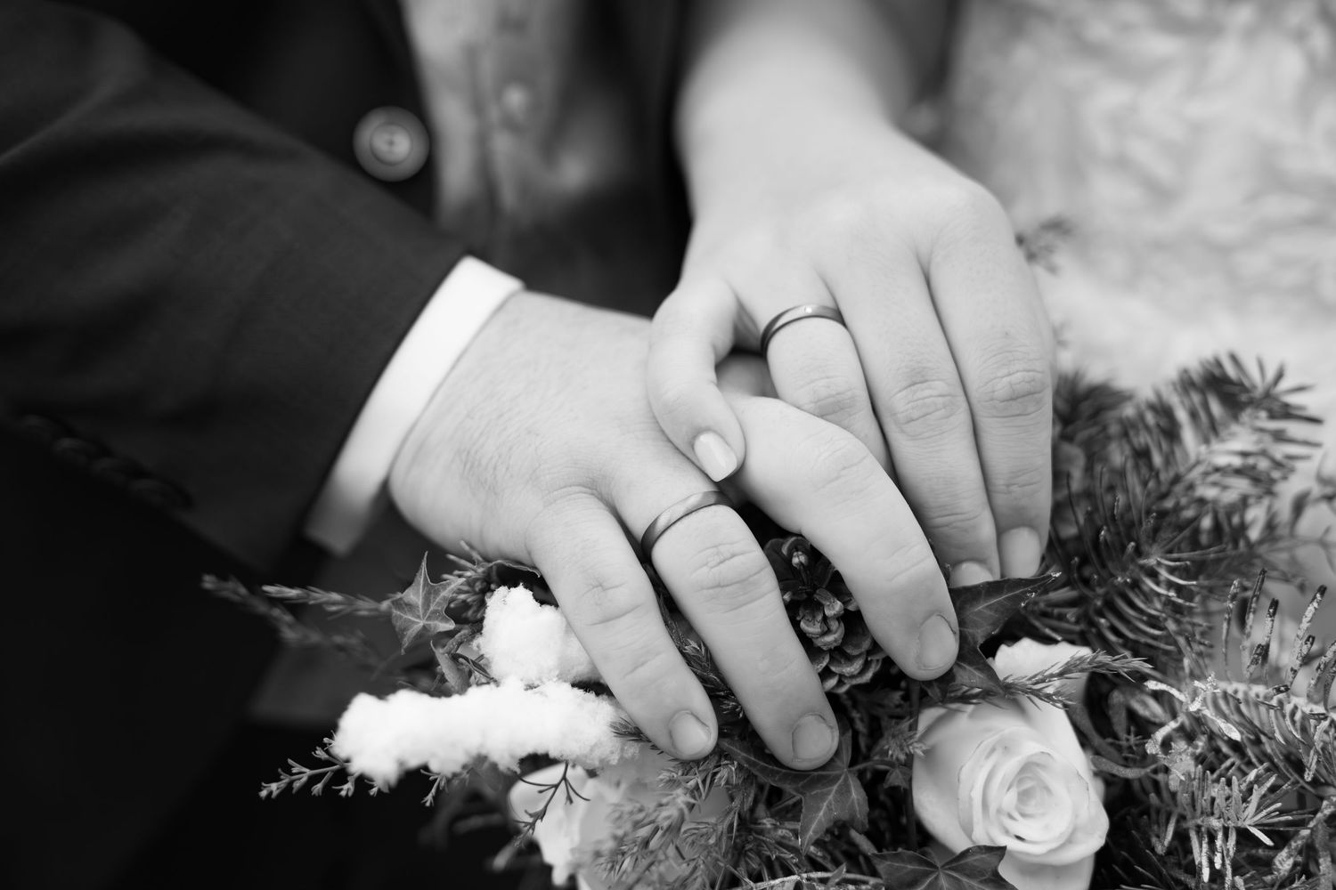 Black and white close-up of hands holding a wedding bouquet with roses.