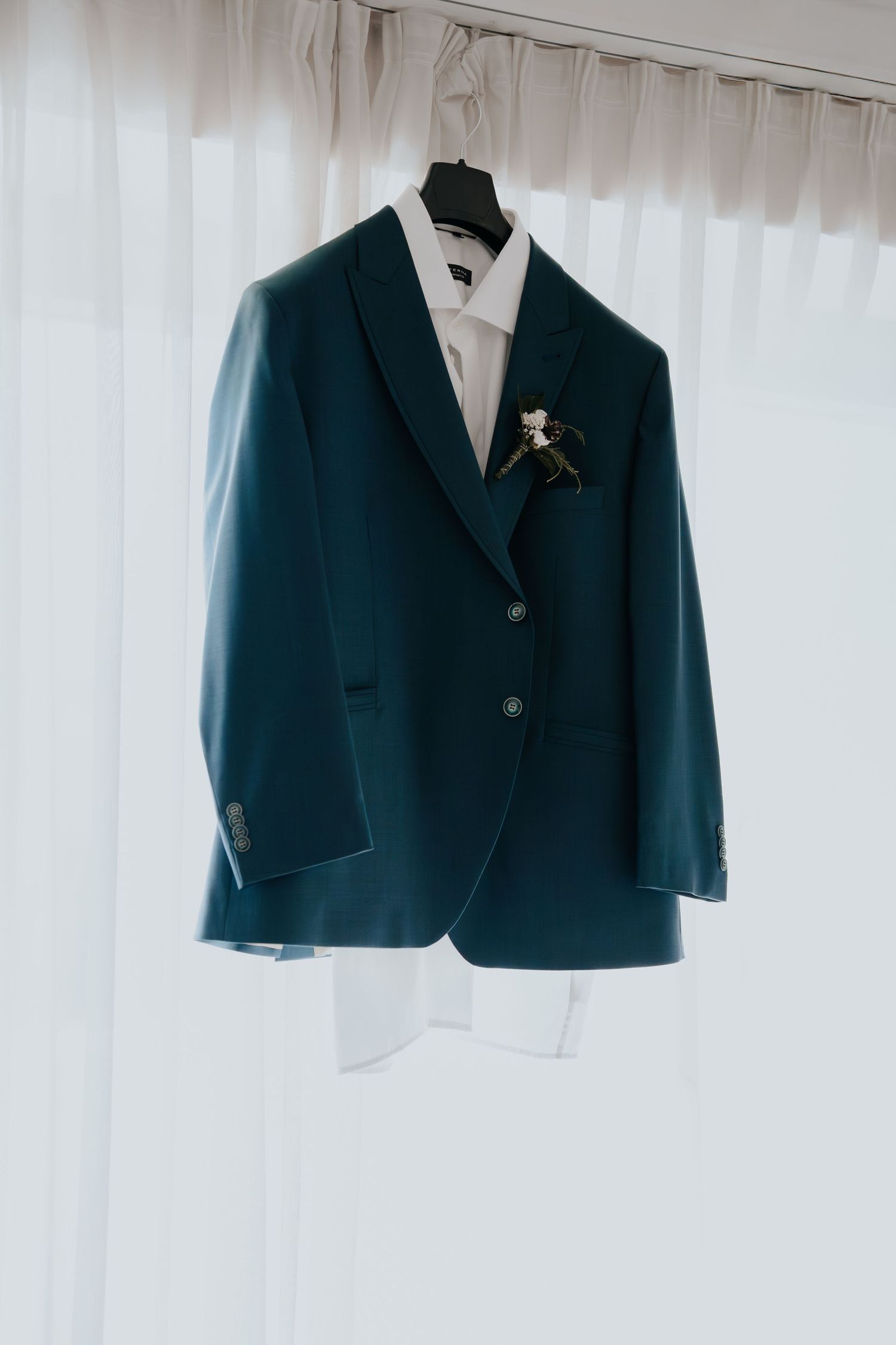 Navy blue suit jackets hanging on white hangers against a light background.