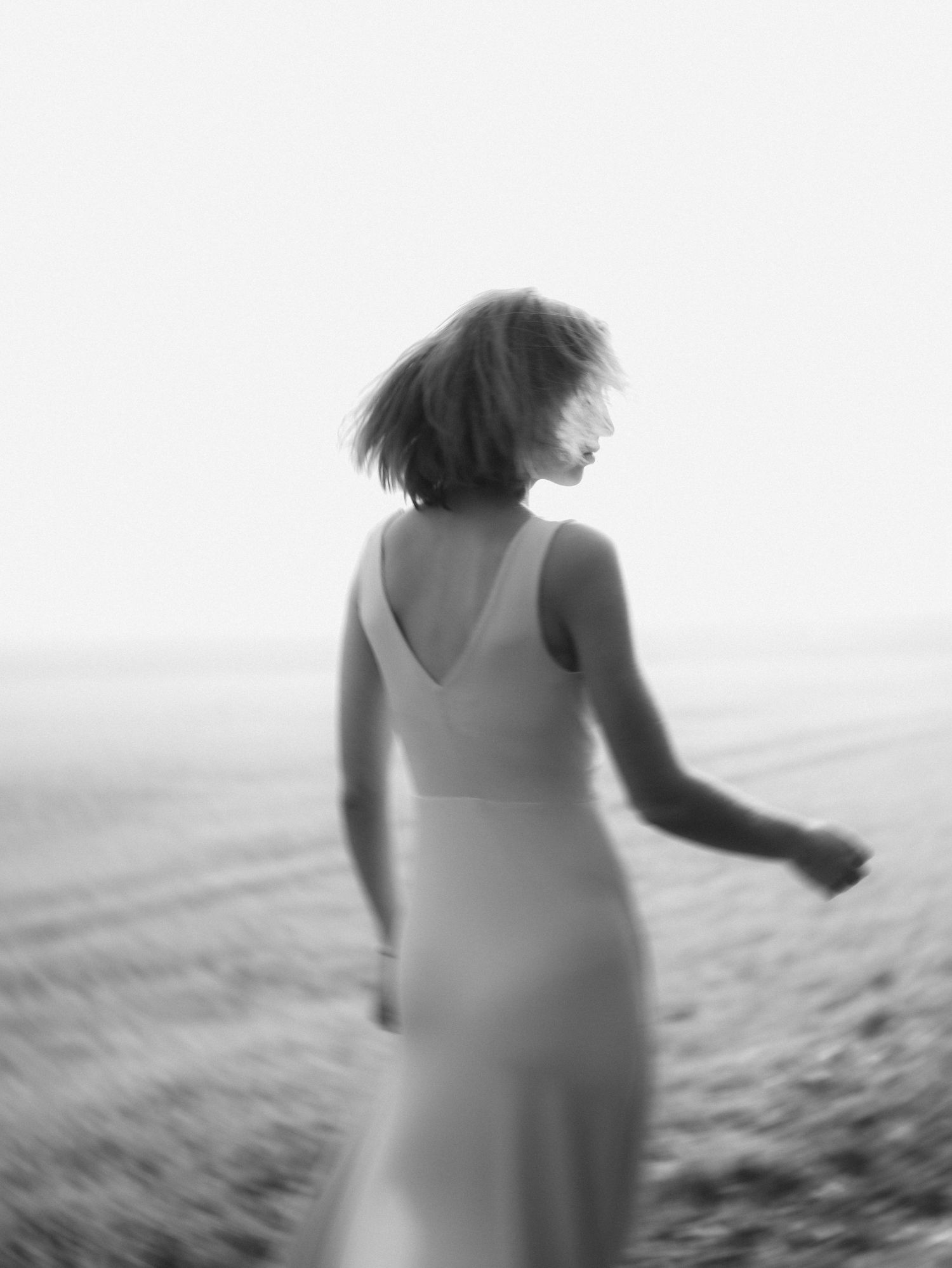 A dreamy black and white portrait of a woman in a flowing dress against a misty background.