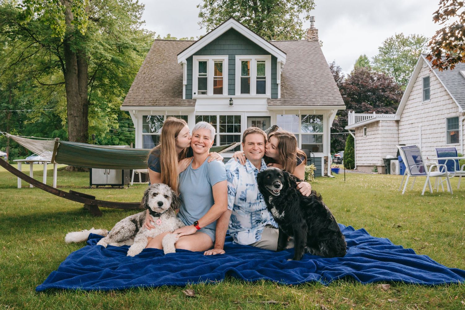 Family sitting on blanket with two dogs during Finger Lakes family mini session, Upstate NY photography outdoors, coordinating outfits