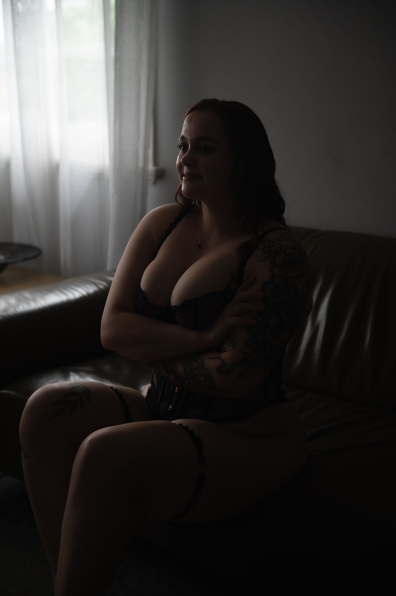 Woman poses on dark lounge in moody lighting for boudoir photoshoot at SeduXion Studio in Mandurah WA. Boudoir photographer Mandurah