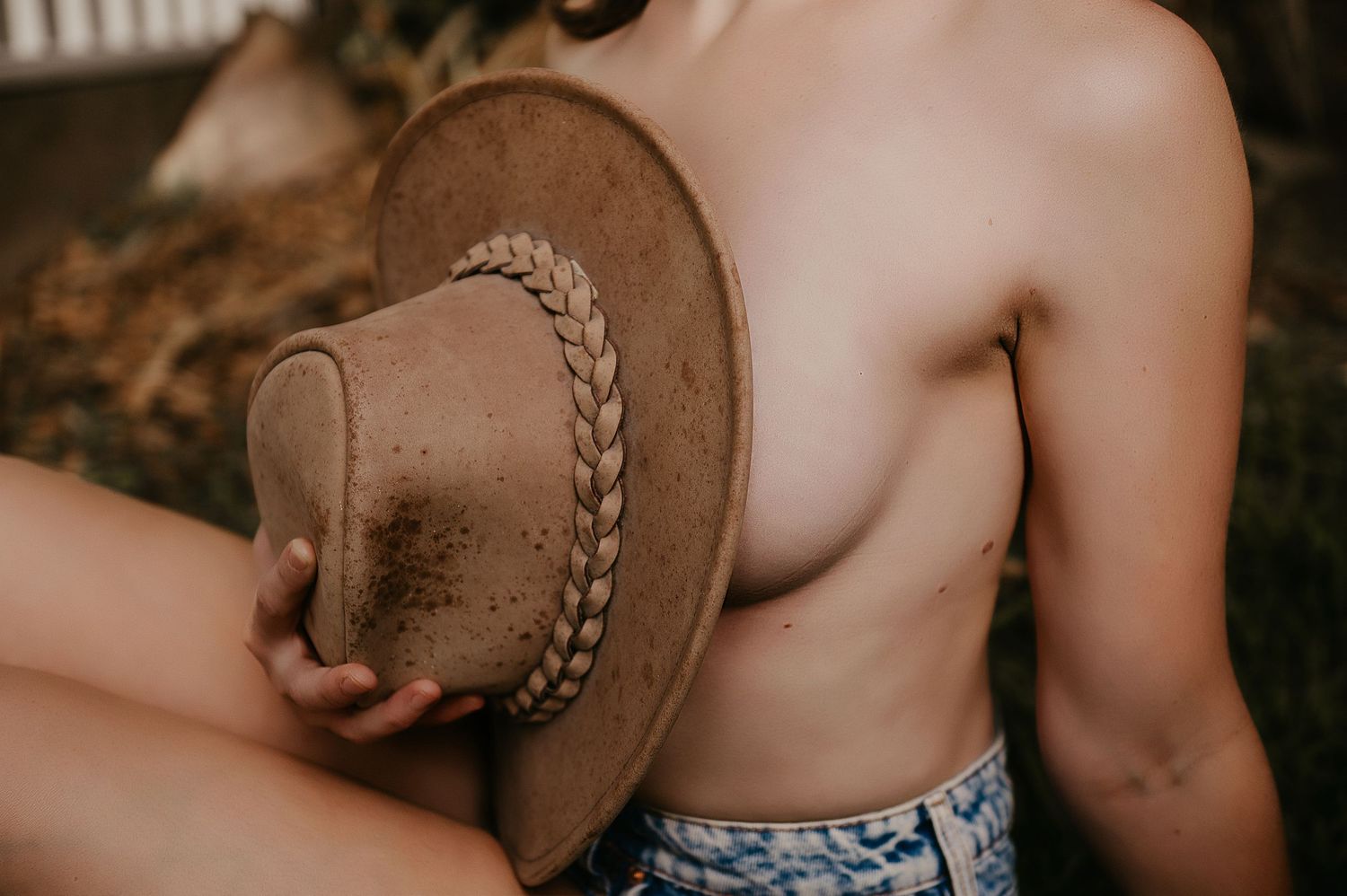Woman poses with cowboy hat in field for boudoir photographer SeduXion Studio in Bunbury WA
