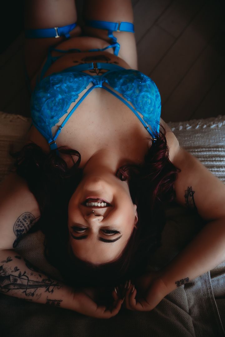 A boudoir portrait featuring blue lace lingerie in moody lighting on dark textured couch in Mandurah Western Australia with SeduXion Studio