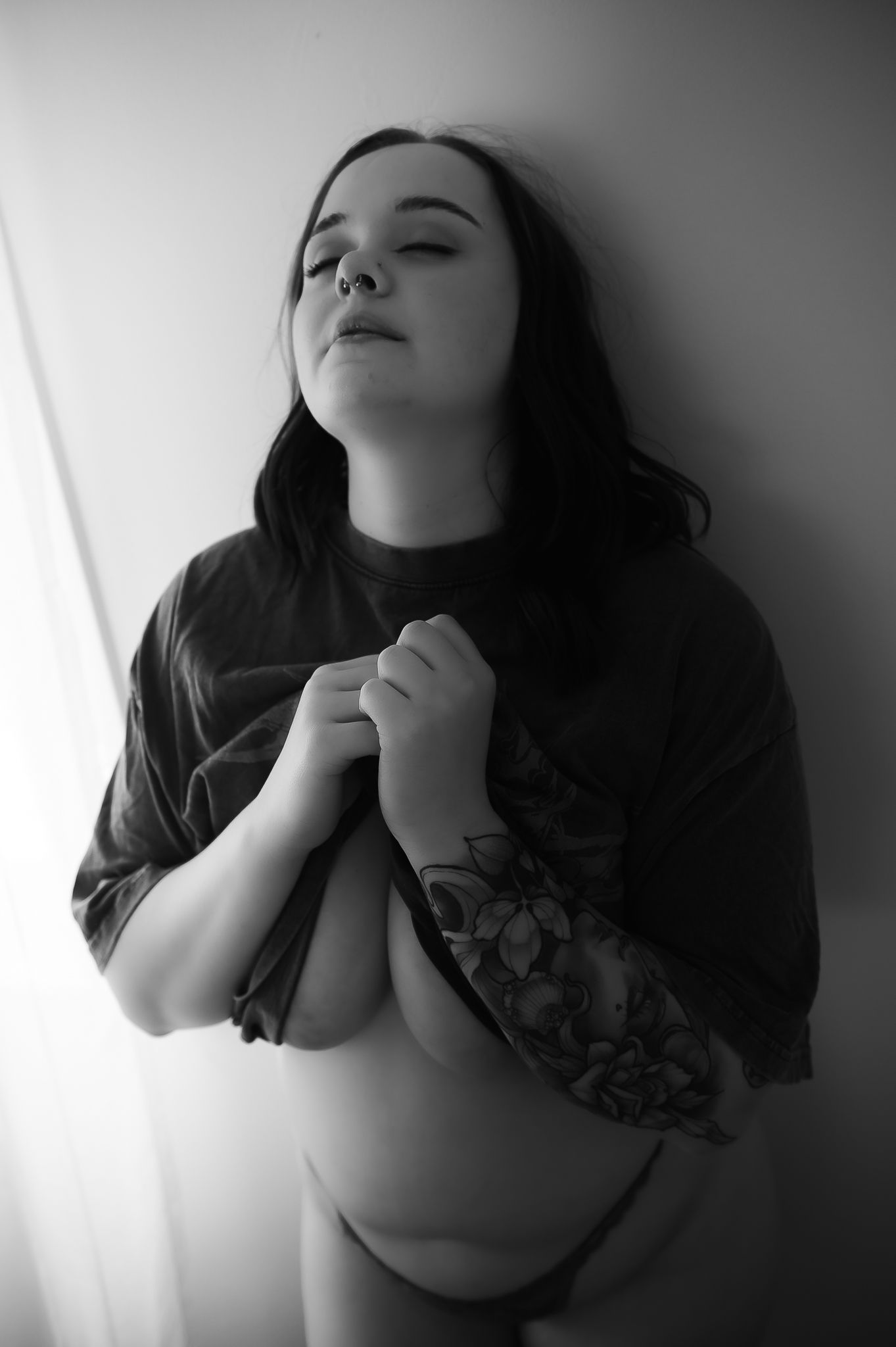 Black and white photo of woman posing against wall for boudoir photoshoot at SeduXion Studio in Mandurah WA. Boudoir photographer Mandurah
