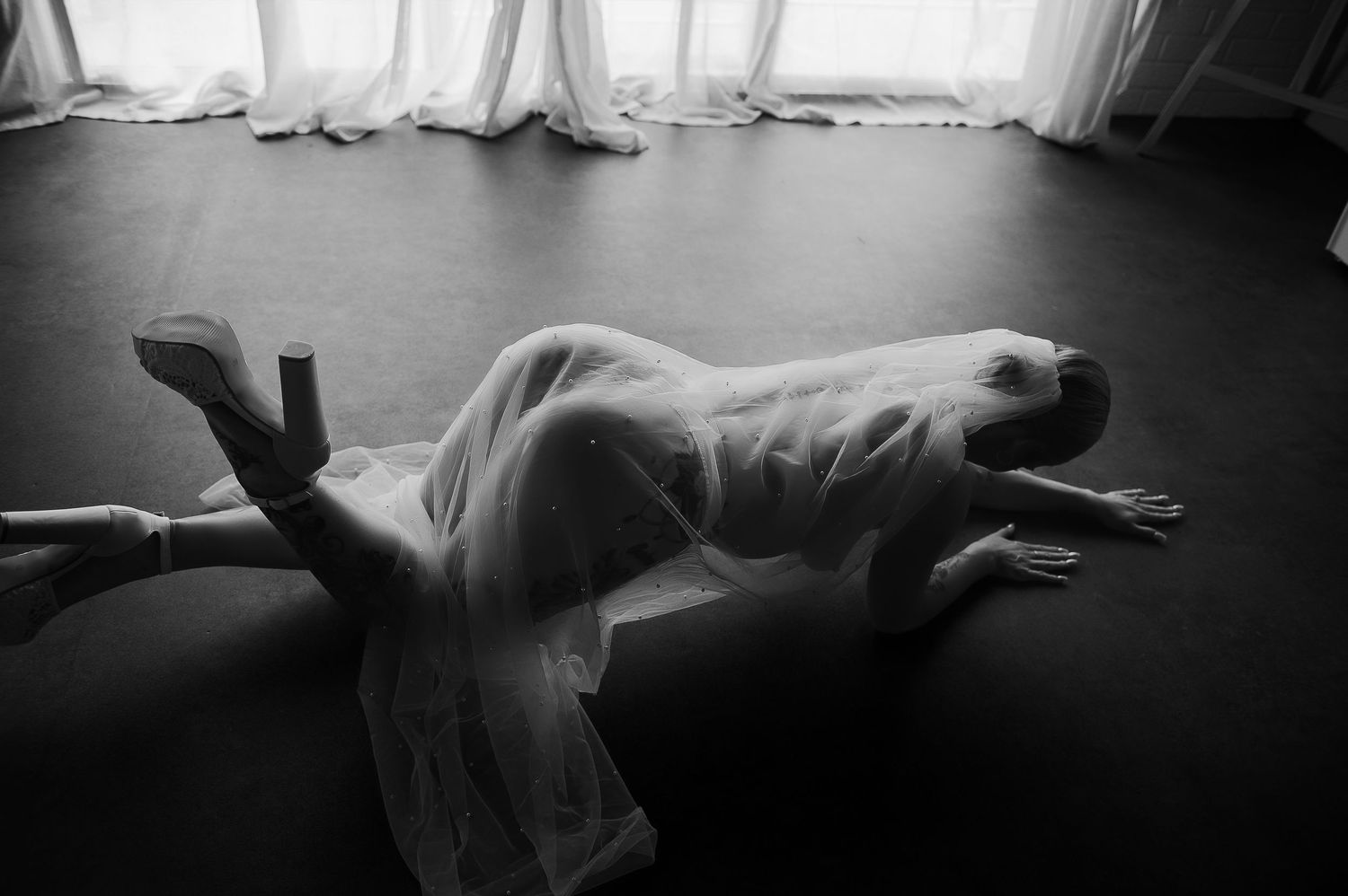 Black and white photo of a woman draped in sheer white veil for boudoir photographer Perth, SeduXion Studio