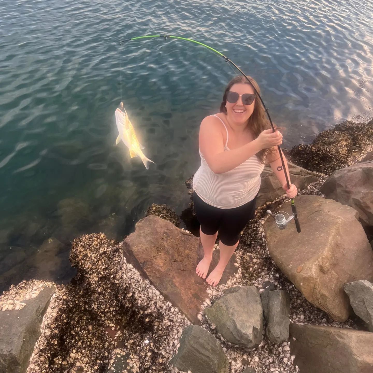 An old photo of SeduXion Studio owner, Paige, poses with fishing rod showing fish she caught. Showing body weight fluctuations