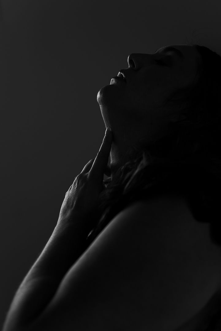 Black and white silhouetted image of plus-size woman posing for boudoir photoshoot with finger under chin in Mandurah Western Australia