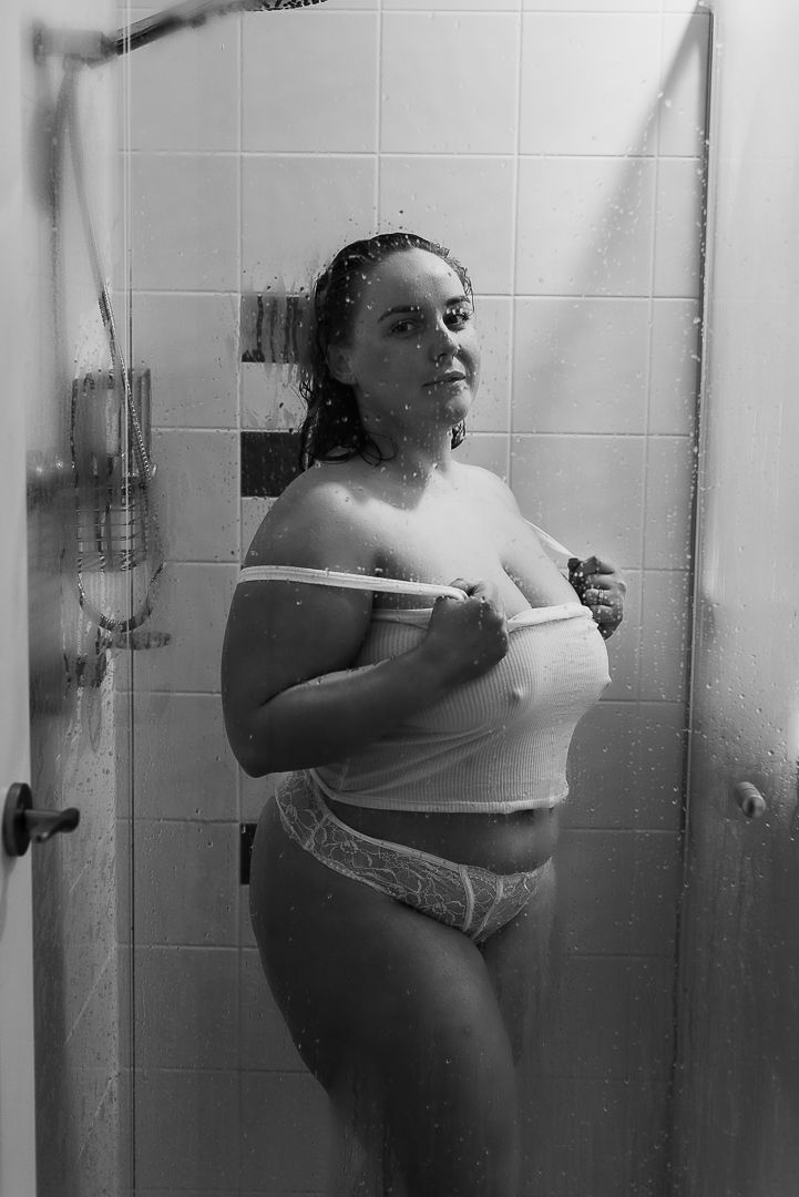 A black and white photograph showing a woman in a white shirt against bathroom tiles at SeduXion Studio in Mandurah Western Australia
