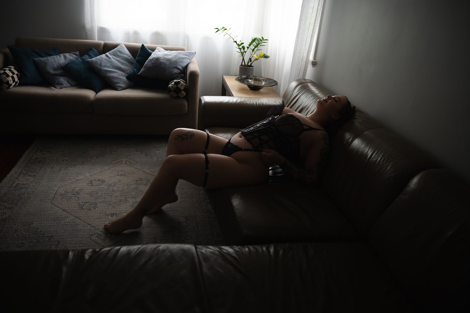 Woman poses on dark brown lounge for boudoir photoshoot at SeduXion Studio in Mandurah WA. Boudoir photographer Mandurah