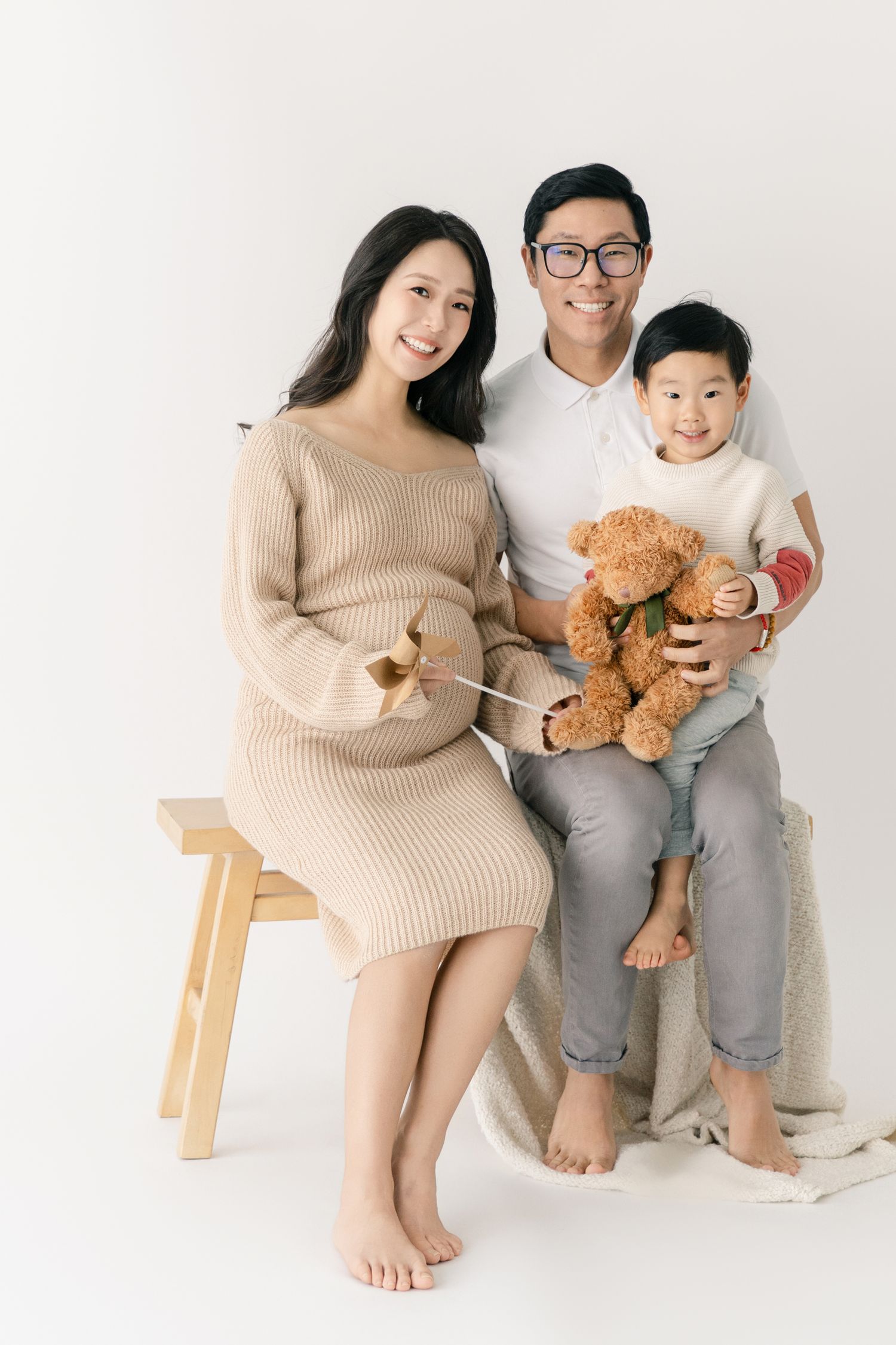 Cozy family maternity session featuring teddy bear and casual poses.
