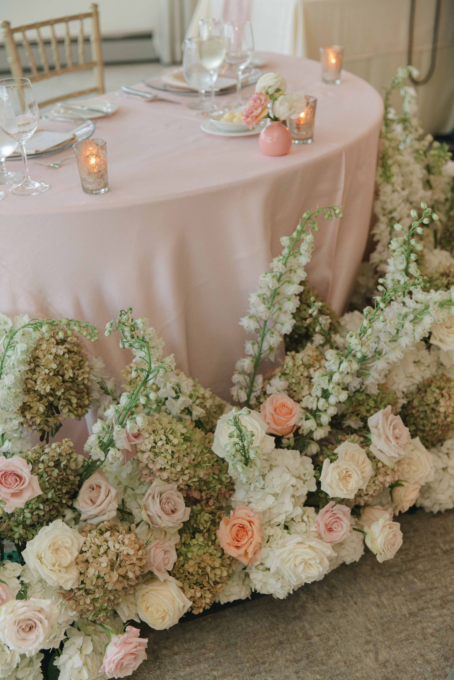 Lush floral arrangement with pink roses and hydrangeas decorating a tablecloth edge.