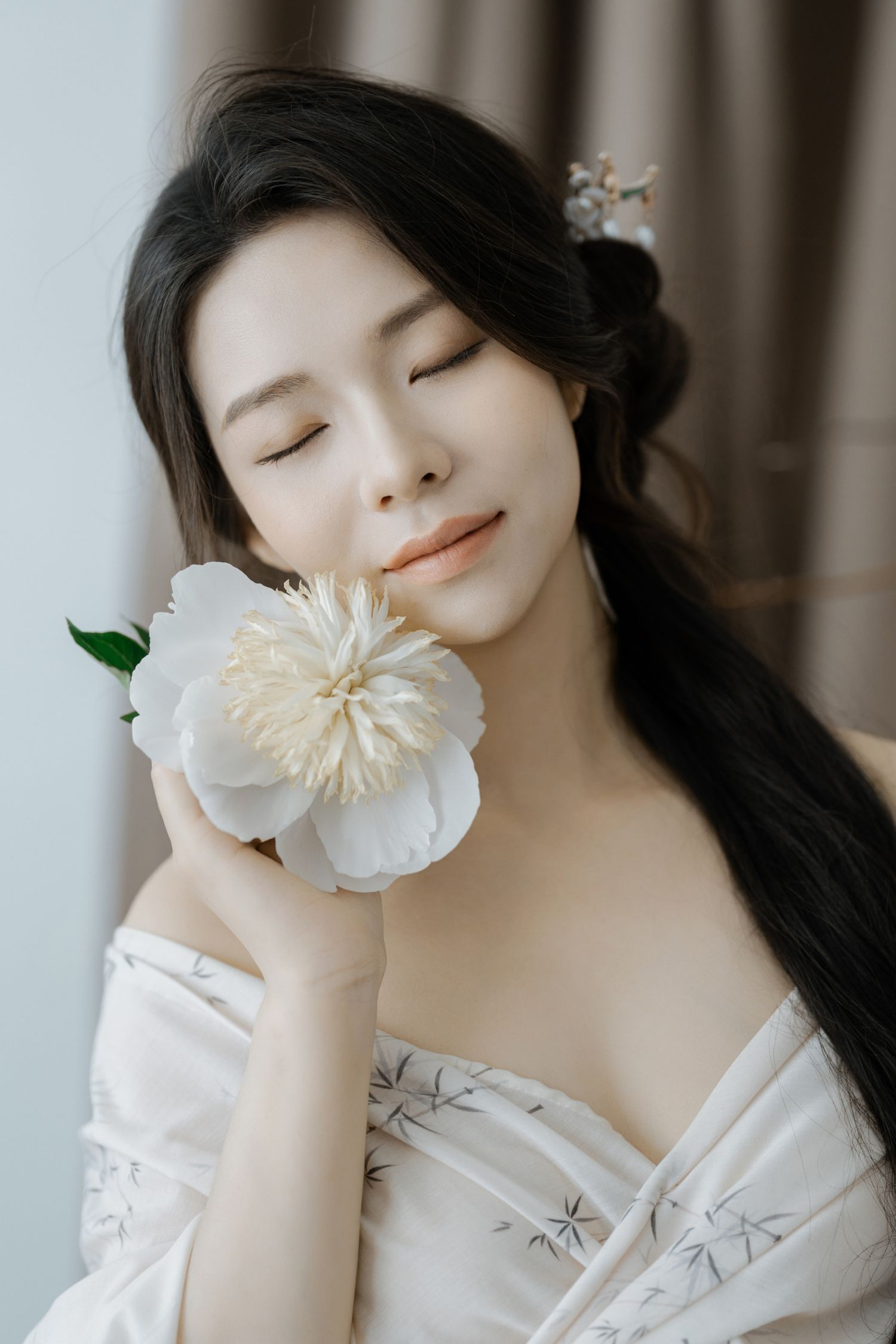 Romantic portrait with white peony flower and delicate off-shoulder dress.