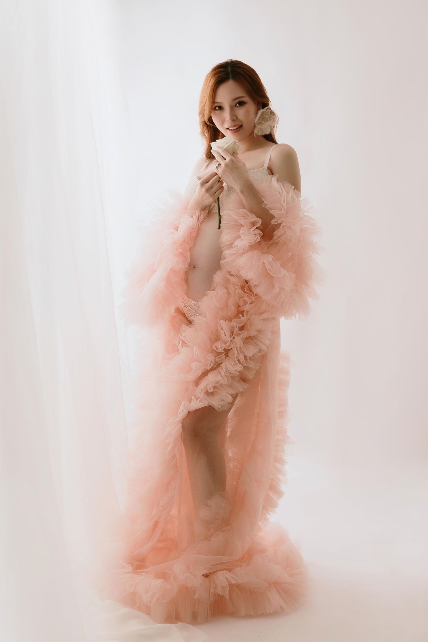Dreamy portrait series in flowing peach tulle gown against white backdrop.