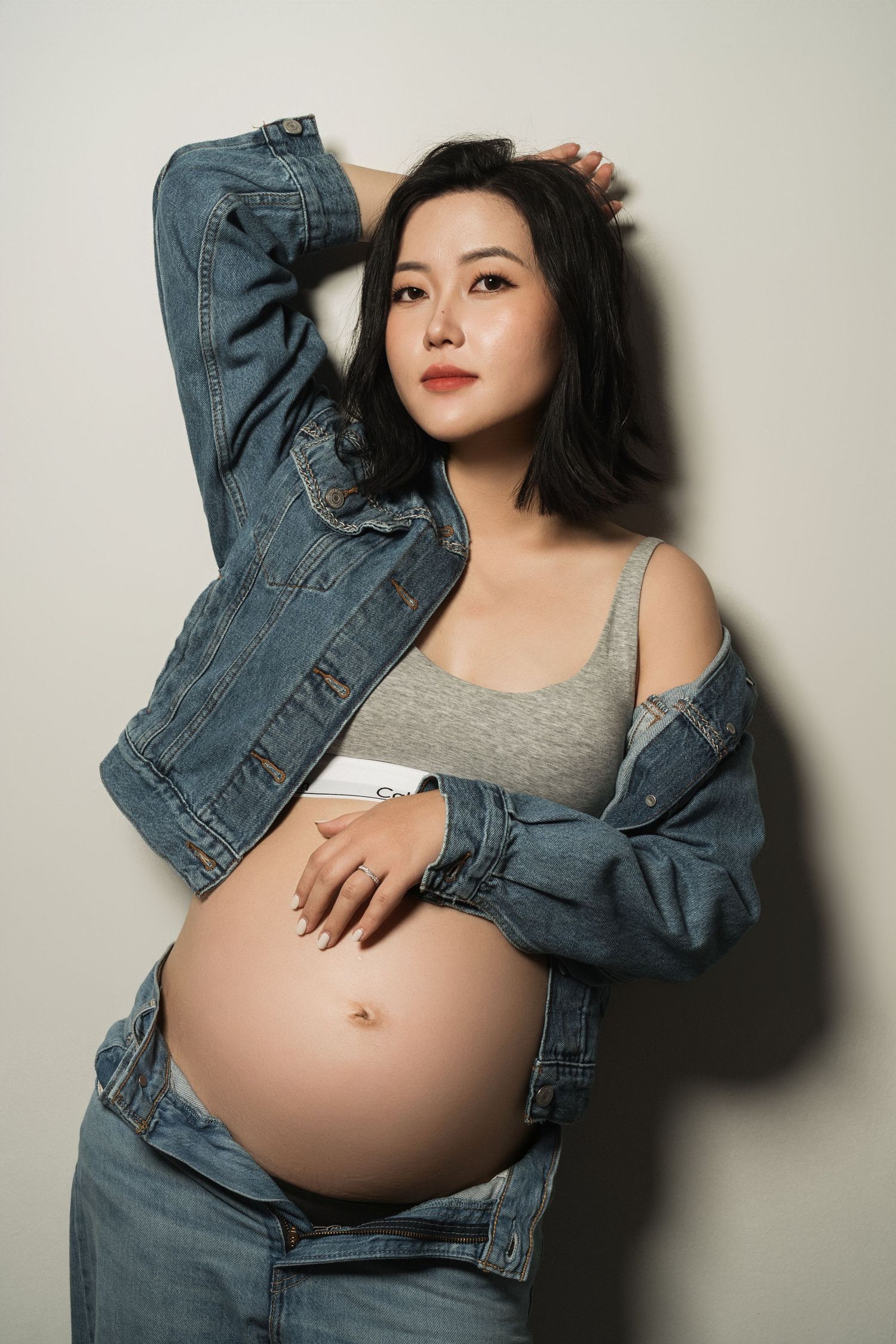 Maternity photos featuring pregnant woman in denim jacket and grey top.
