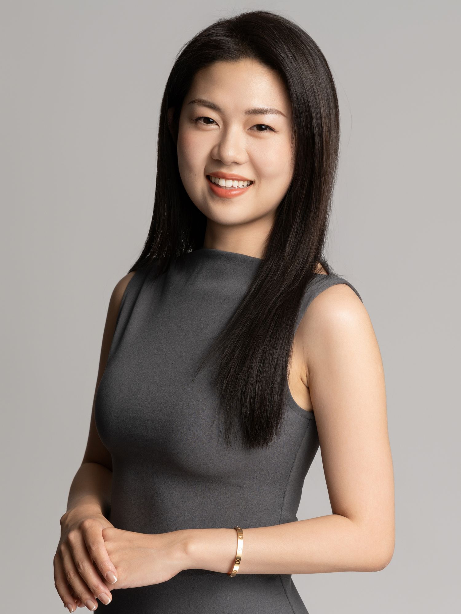 Studio portraits of woman in sleeveless black dress against grey background.