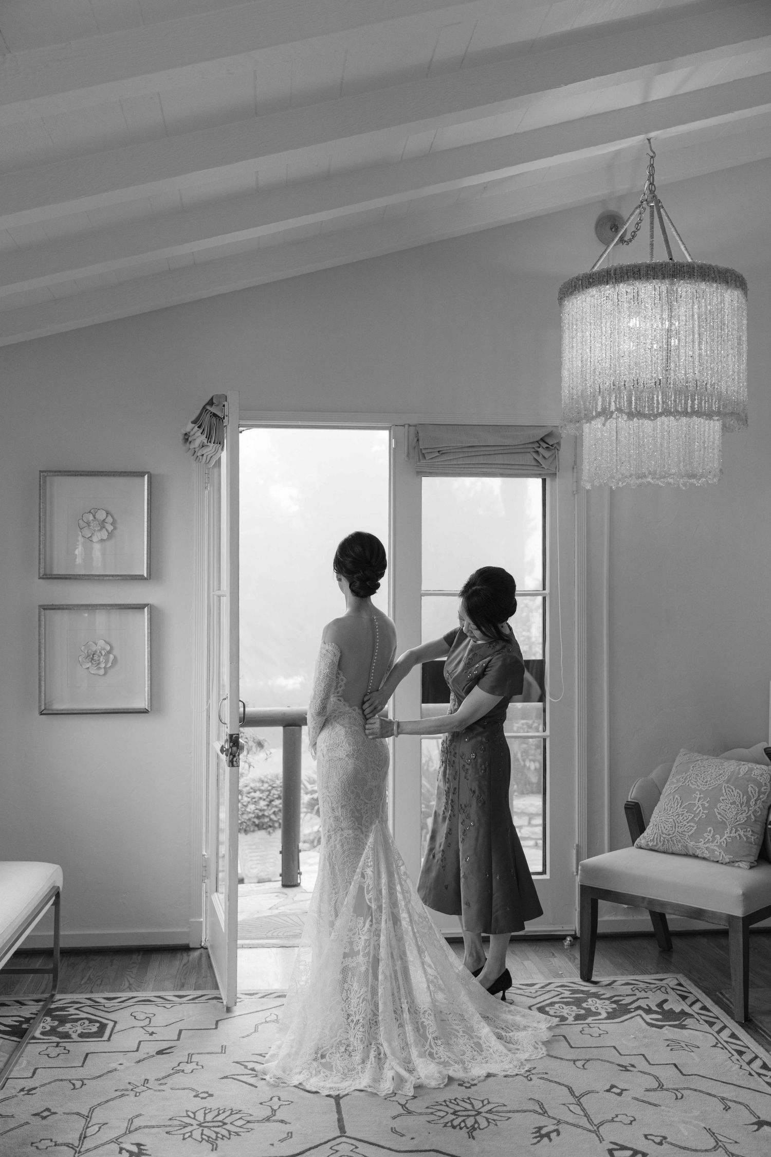 Wedding dress displayed in bright room with crystal chandeliers and patterned floor.