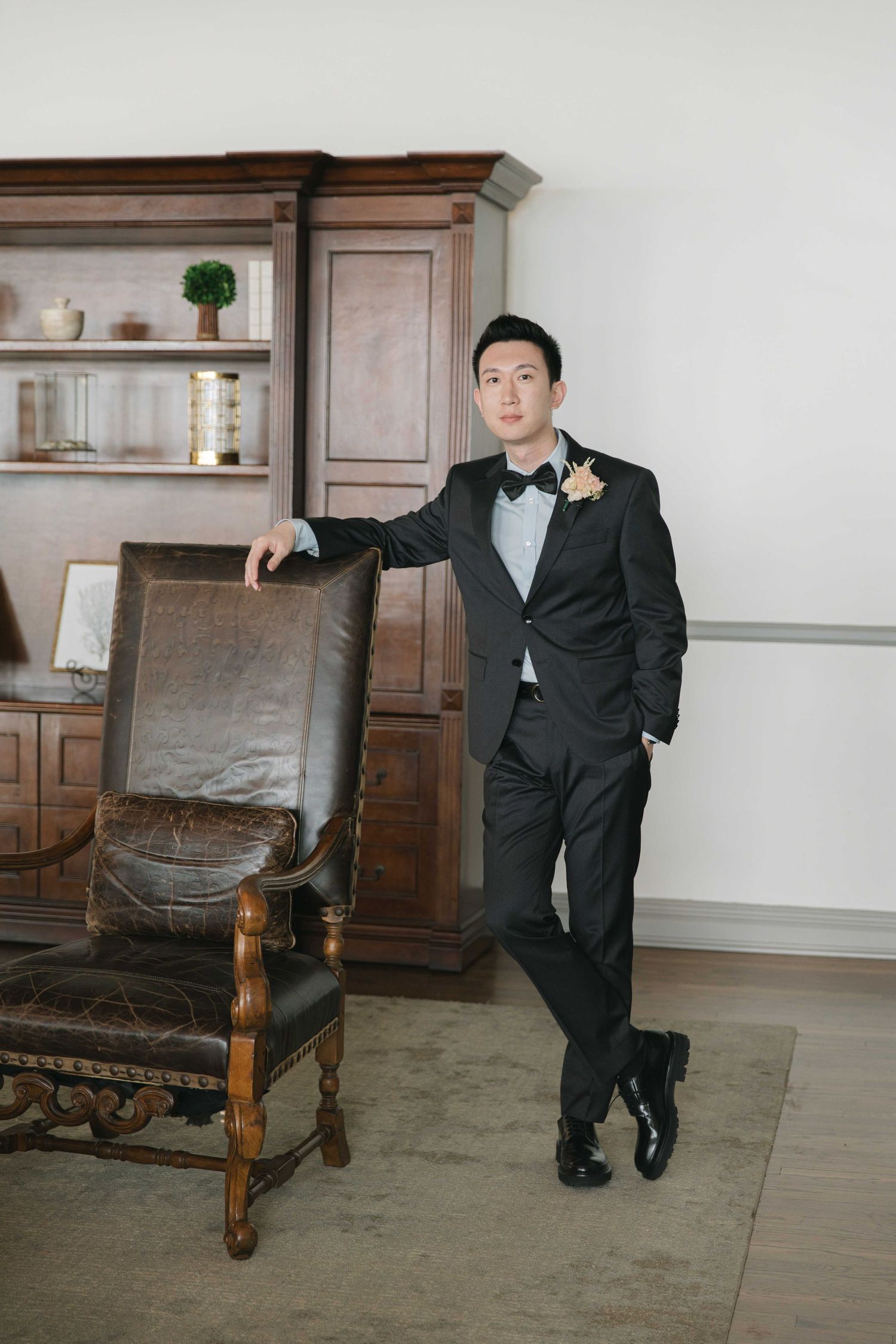 Wedding photography session with classic poses against wooden furniture and white walls.