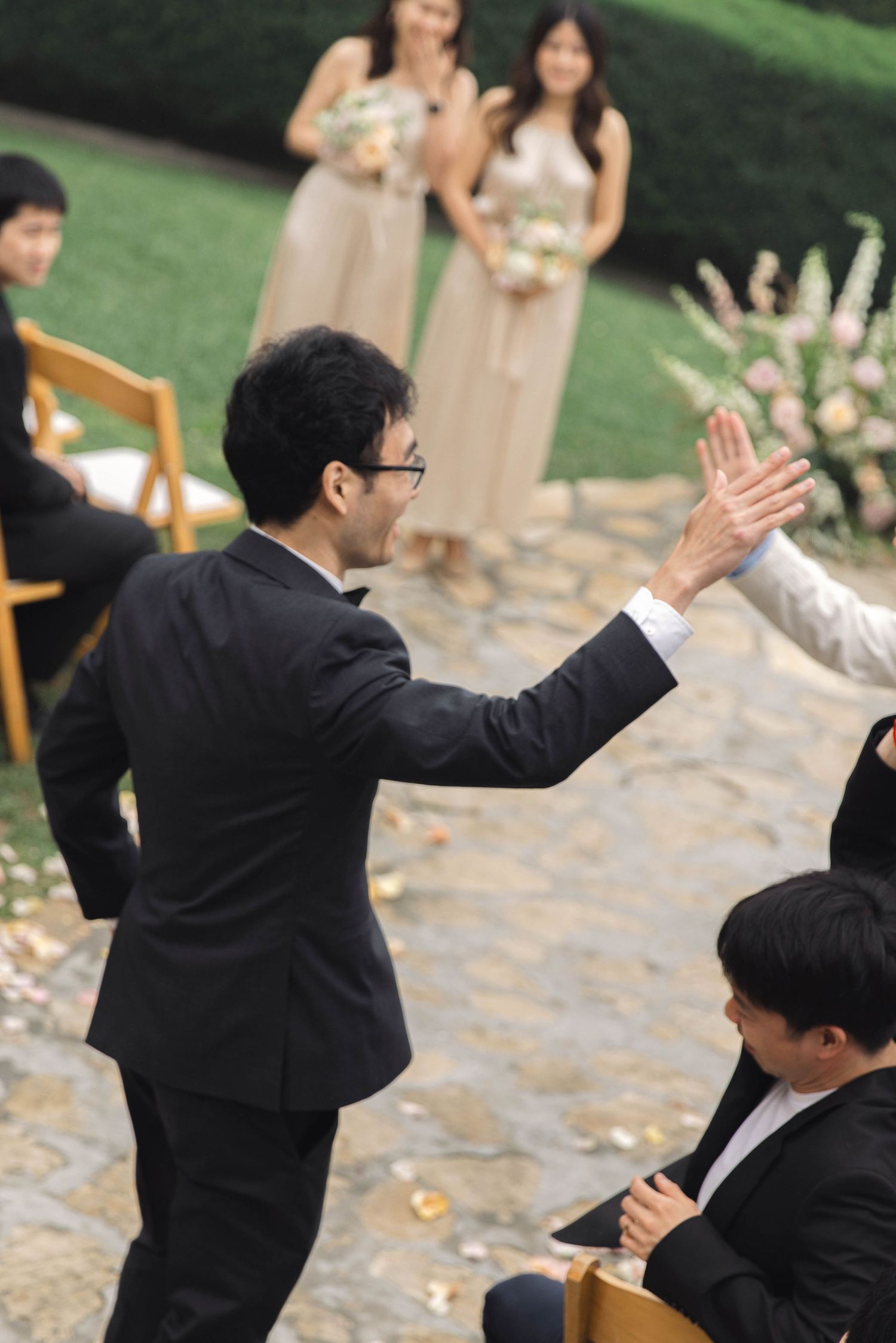 Wedding ceremony attendees engaged in celebratory moment on stone patio surrounded by greenery.