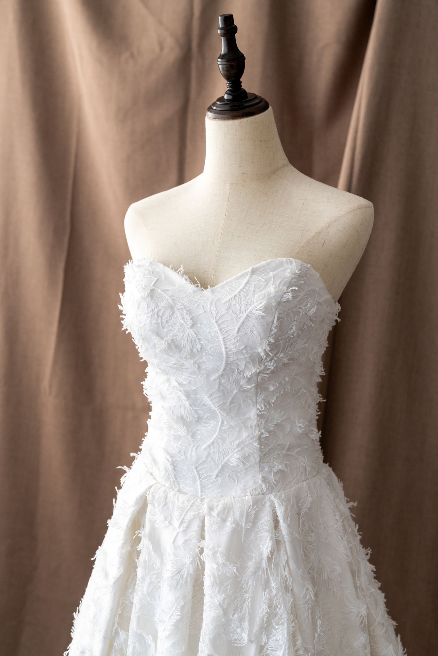 White strapless wedding dress with floral appliques displayed on dress form.