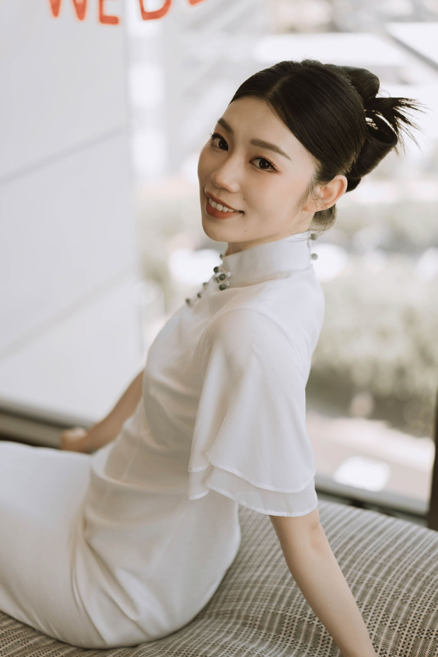 Elegant bridal portraits in a white modern cheongsam against a light background.
