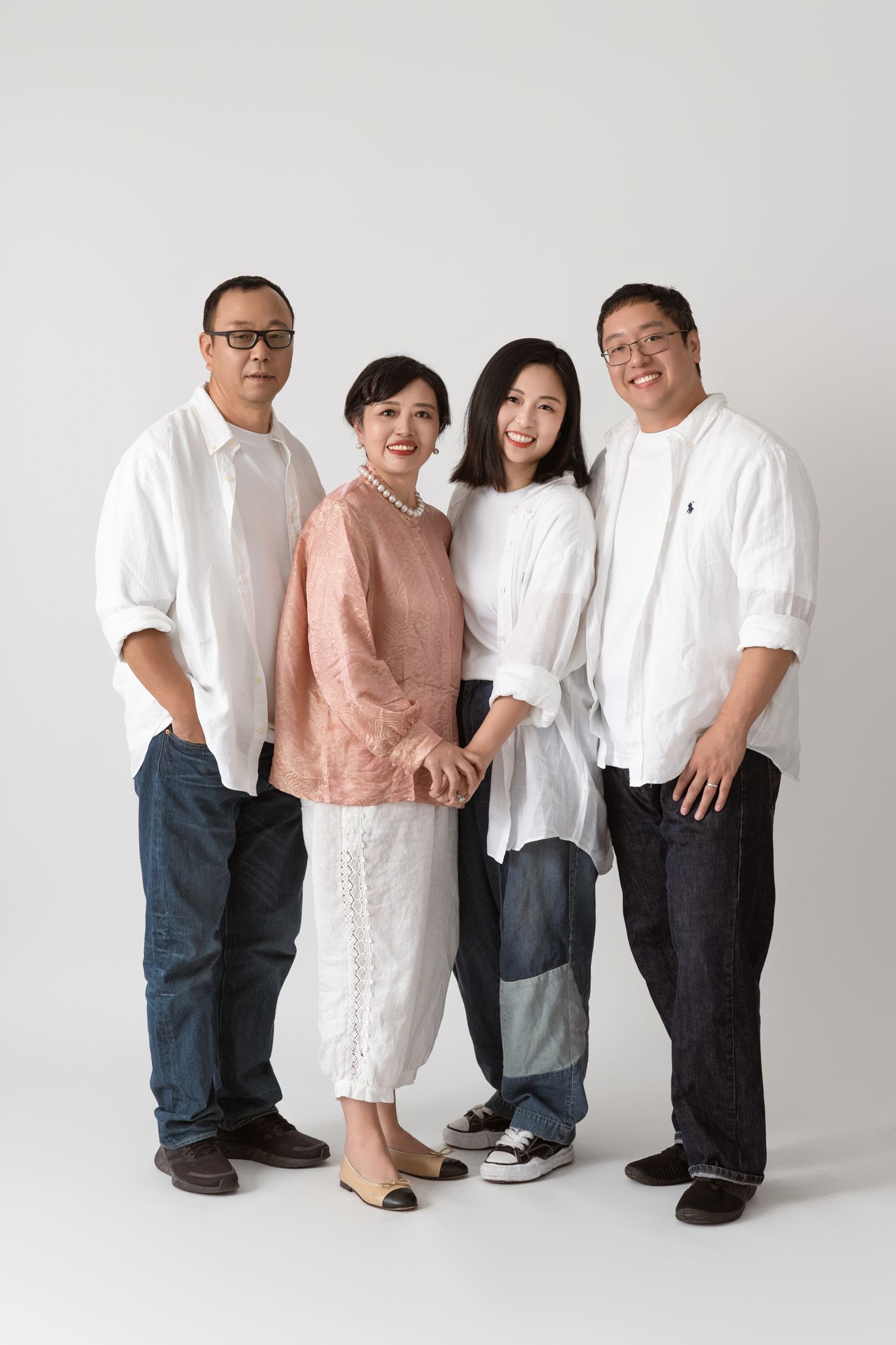 Group photo of family members in casual white and pink outfits against neutral background.