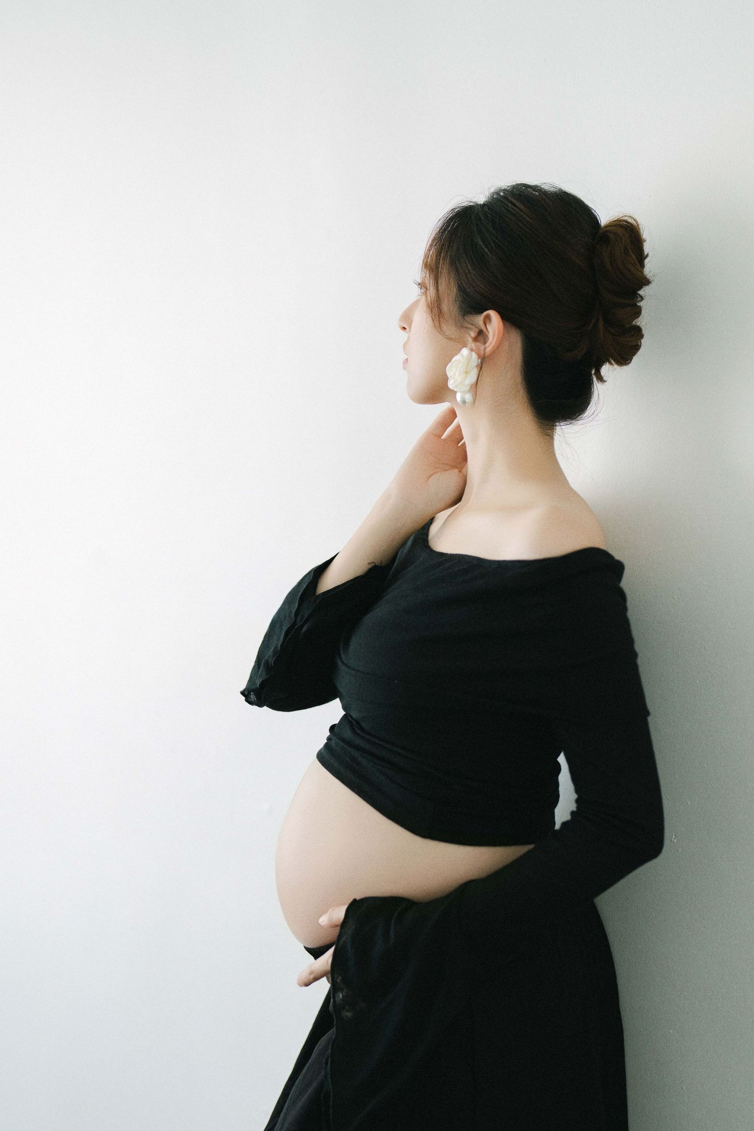 Side profile maternity portraits in black dress against white background.