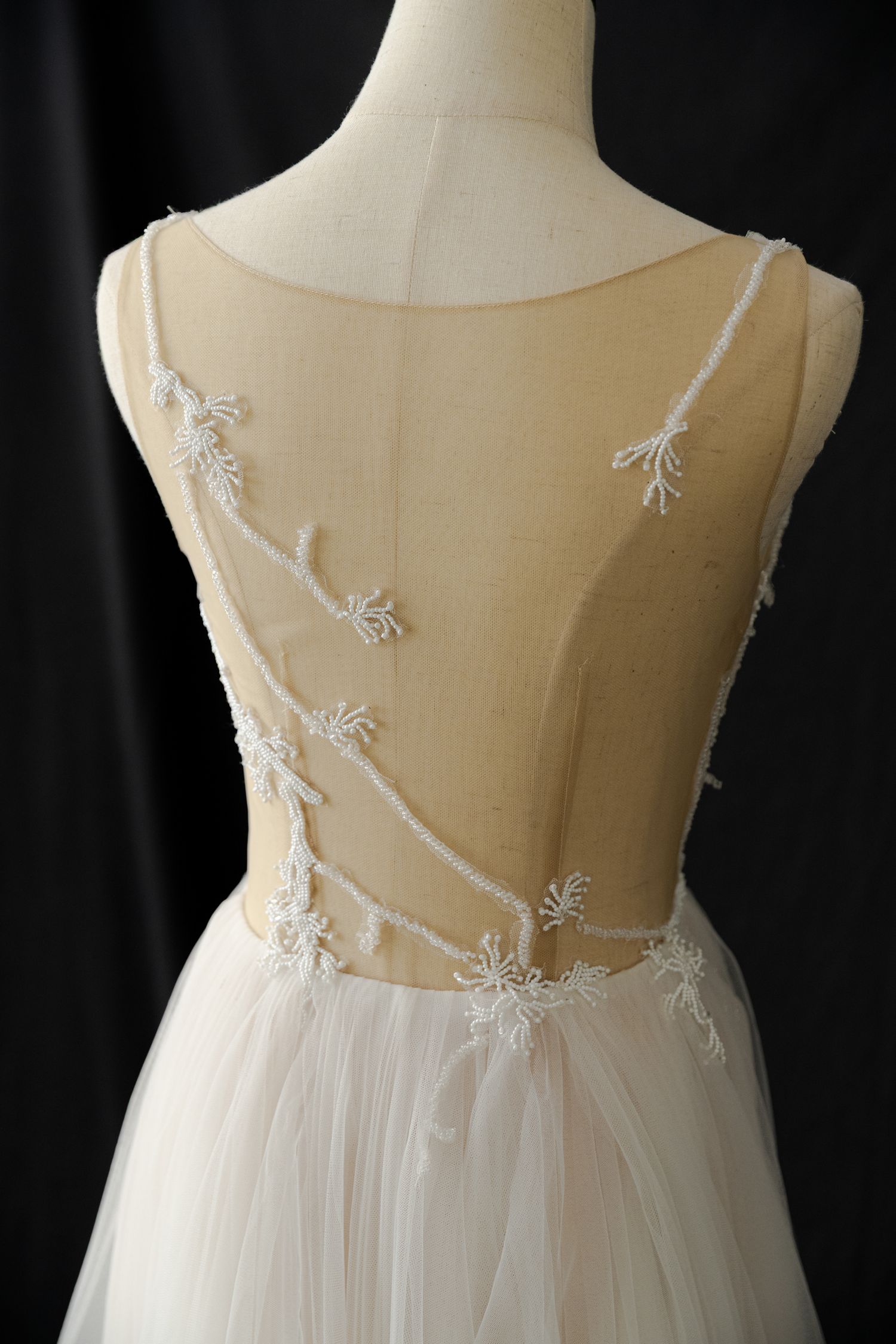 Close-up details of sheer white floral embroidered back on a wedding dress.