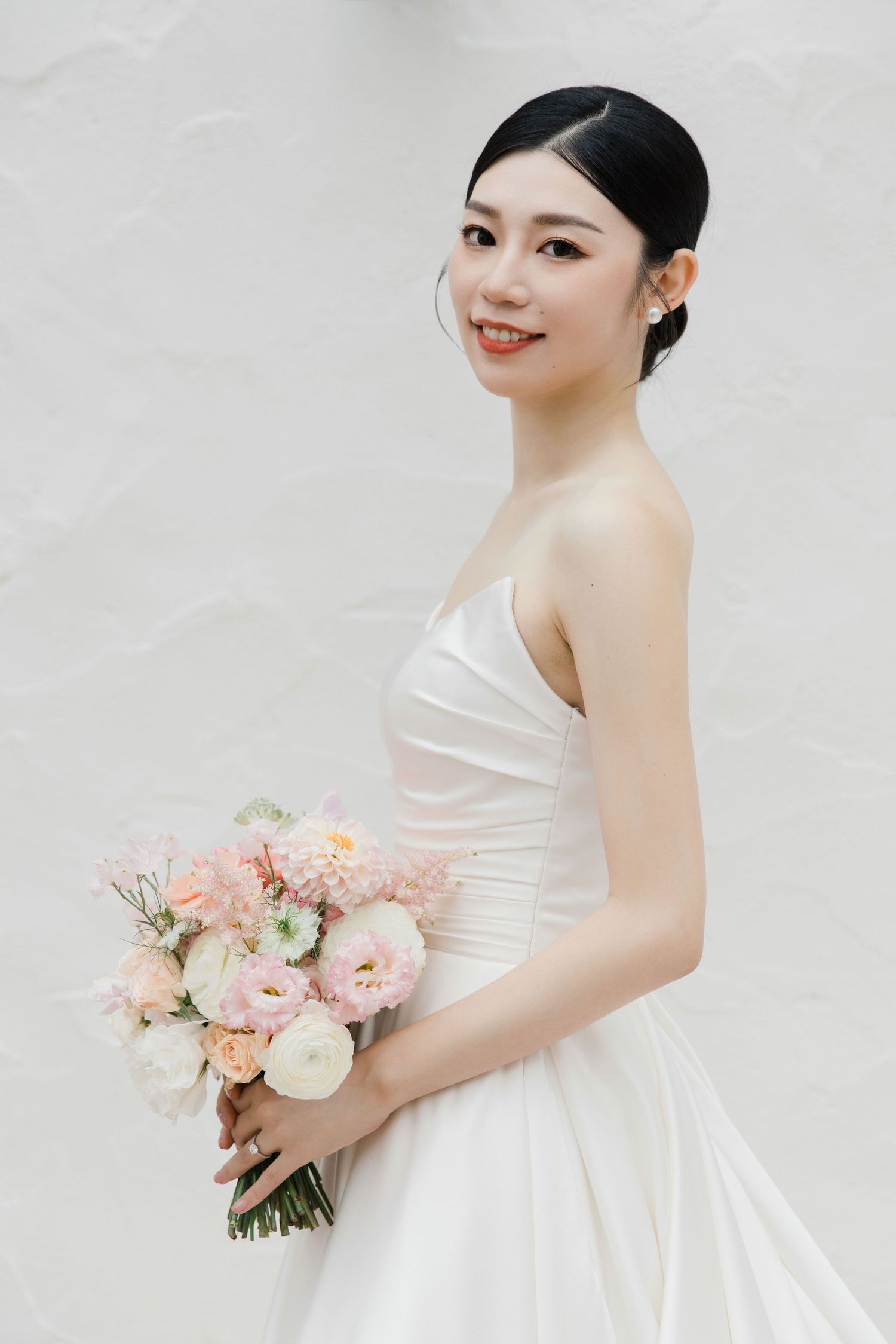 Classic white wedding dress with sweetheart neckline and pink floral bouquet.