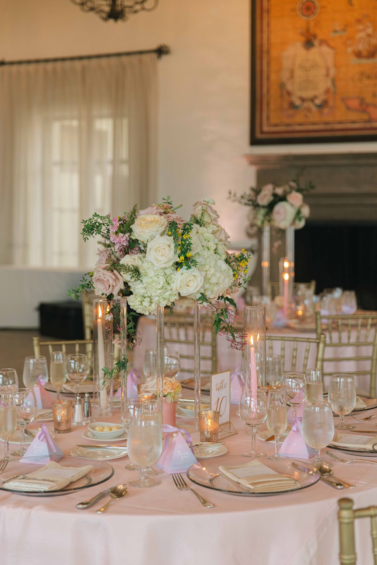 Wedding reception tables set with pink linens, crystal glasses and floral centerpieces.