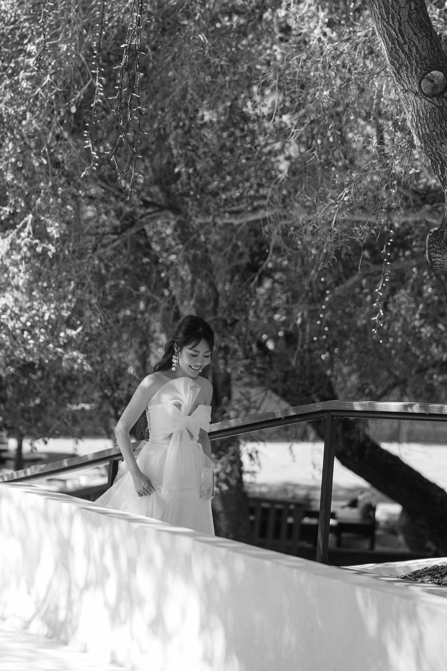 Black and white wedding photo with decorative white elements under trees.