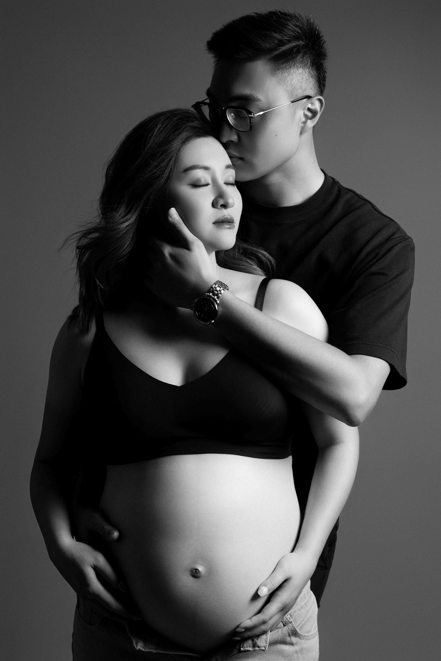 Intimate black and white maternity photos of couple embracing.