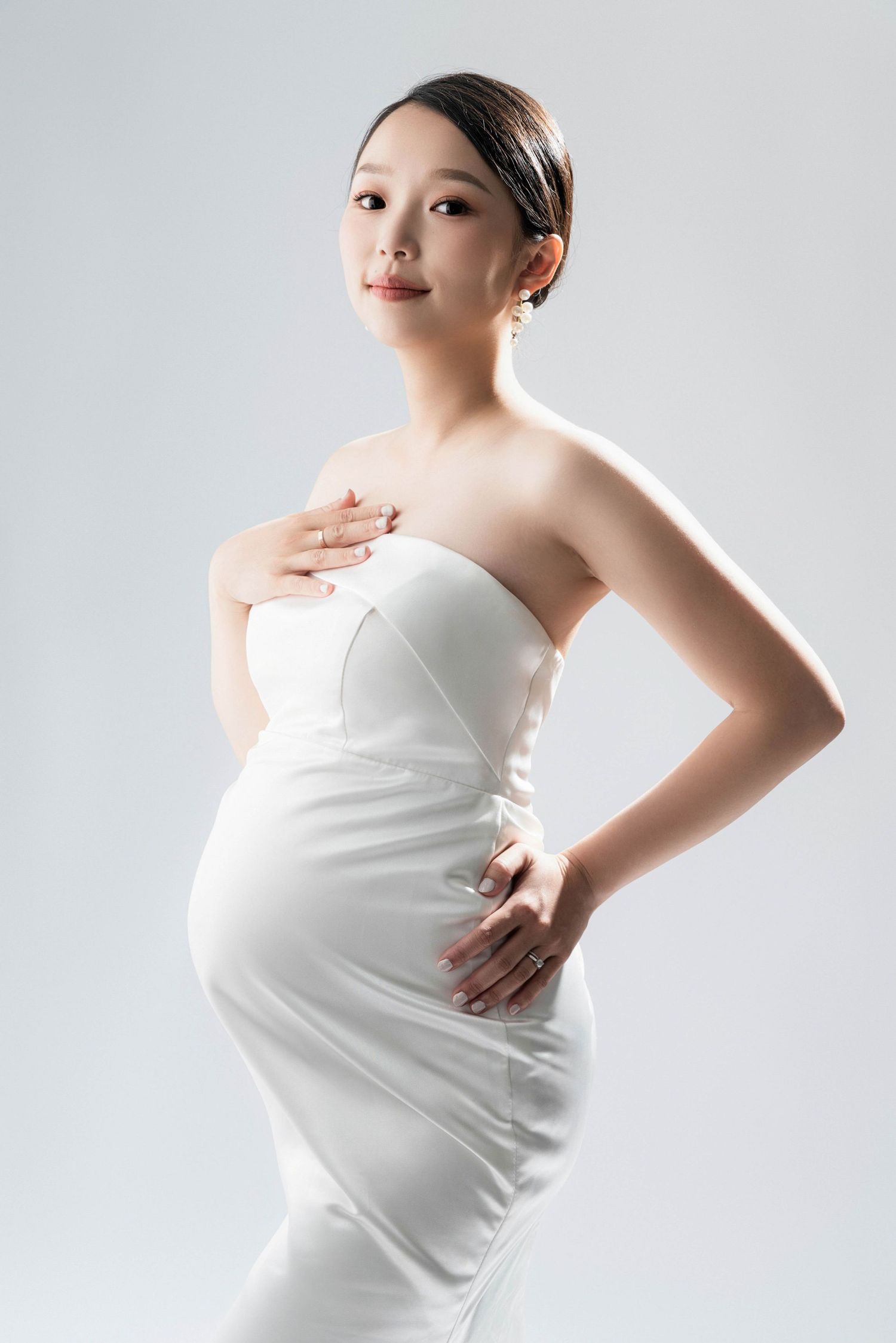 Clean minimalist maternity portraits in white against light background.