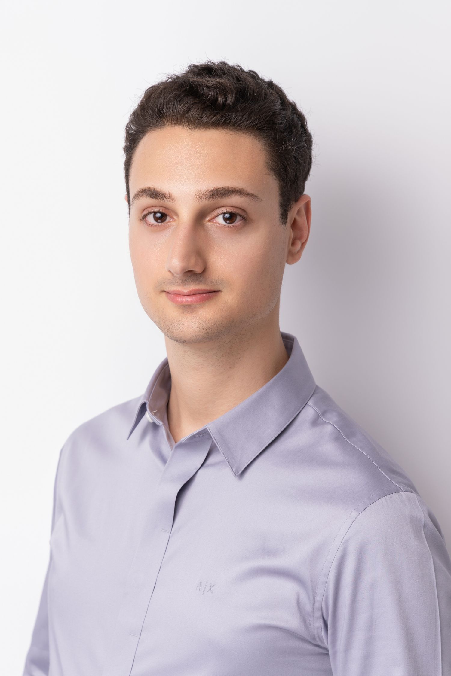 Professional headshot of person in light gray button-down shirt against white background.