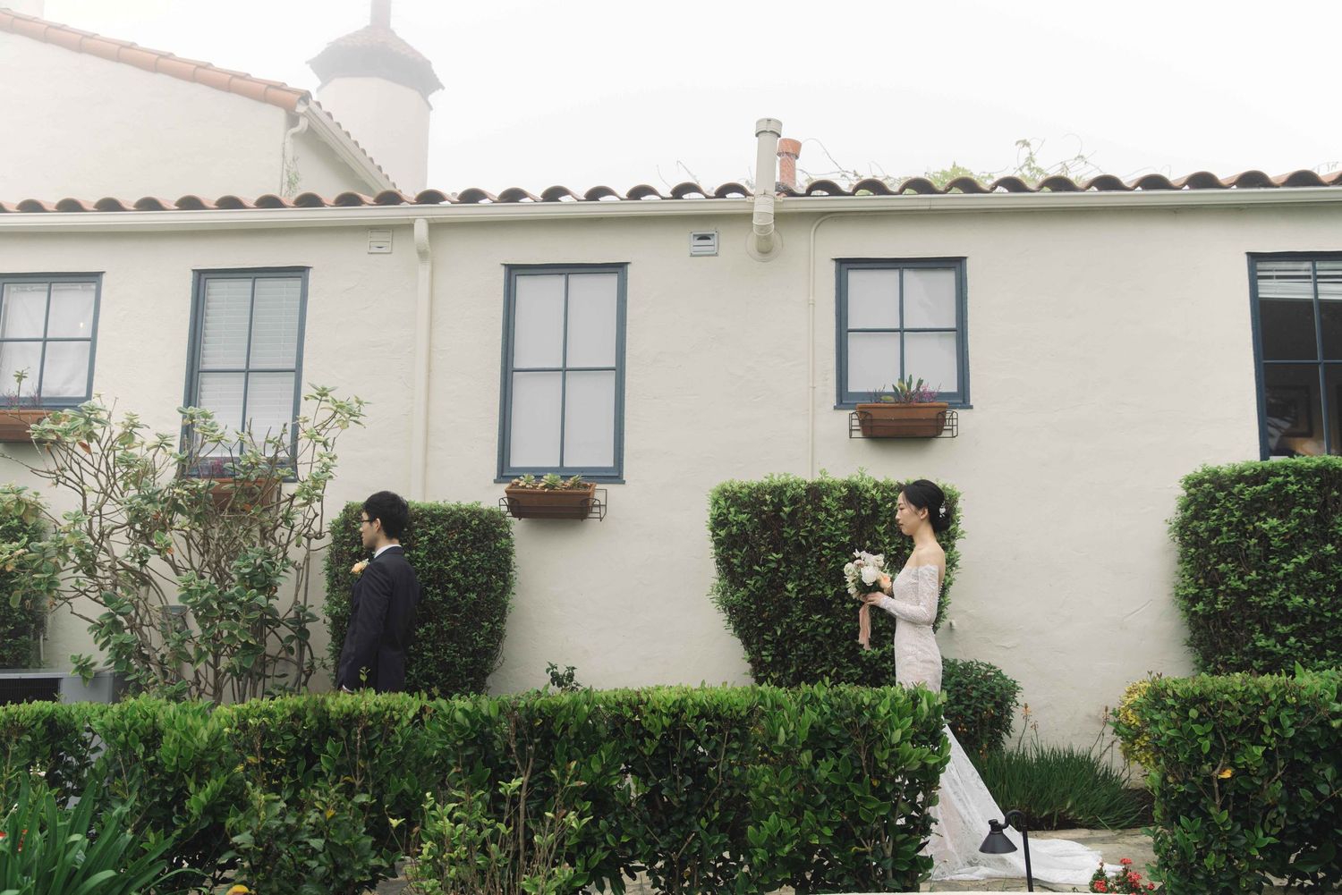 Spanish colonial architecture with white stucco walls and tiled roof creates an elegant wedding backdrop.