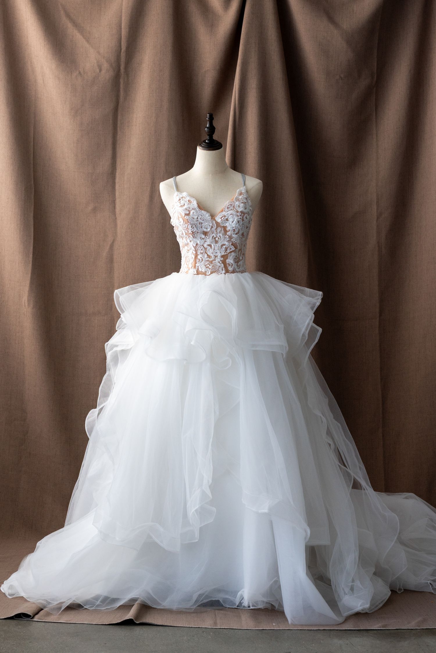 Dramatic wedding dress with layered tulle skirt and embellished bodice displayed on mannequin.