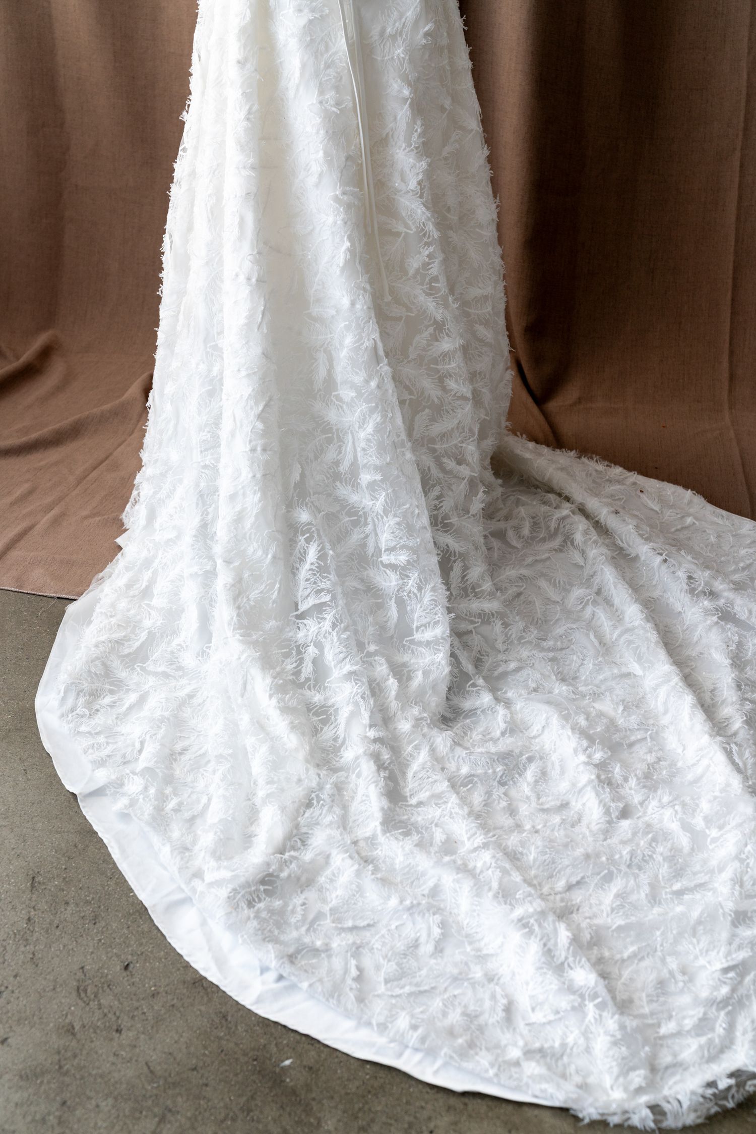 Detailed view of white lace wedding dress train with intricate floral patterns.