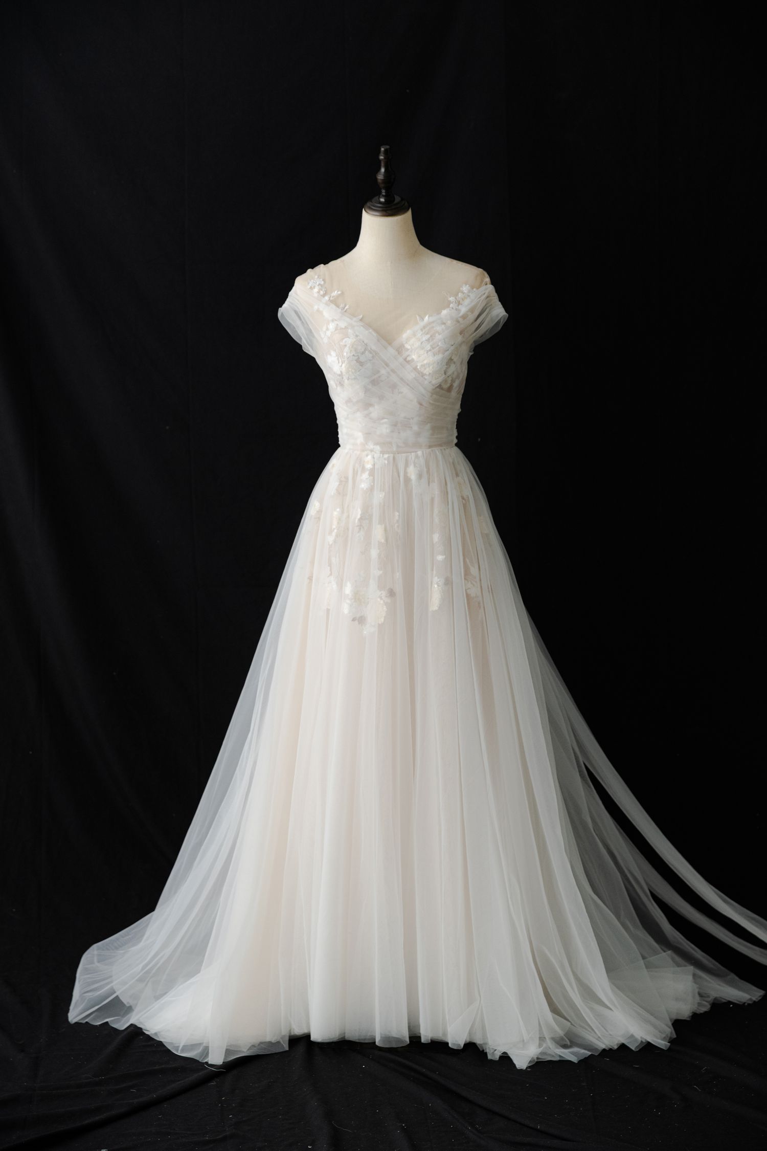 Empire waist wedding gown with off-shoulder neckline and flowing tulle skirt on mannequin.
