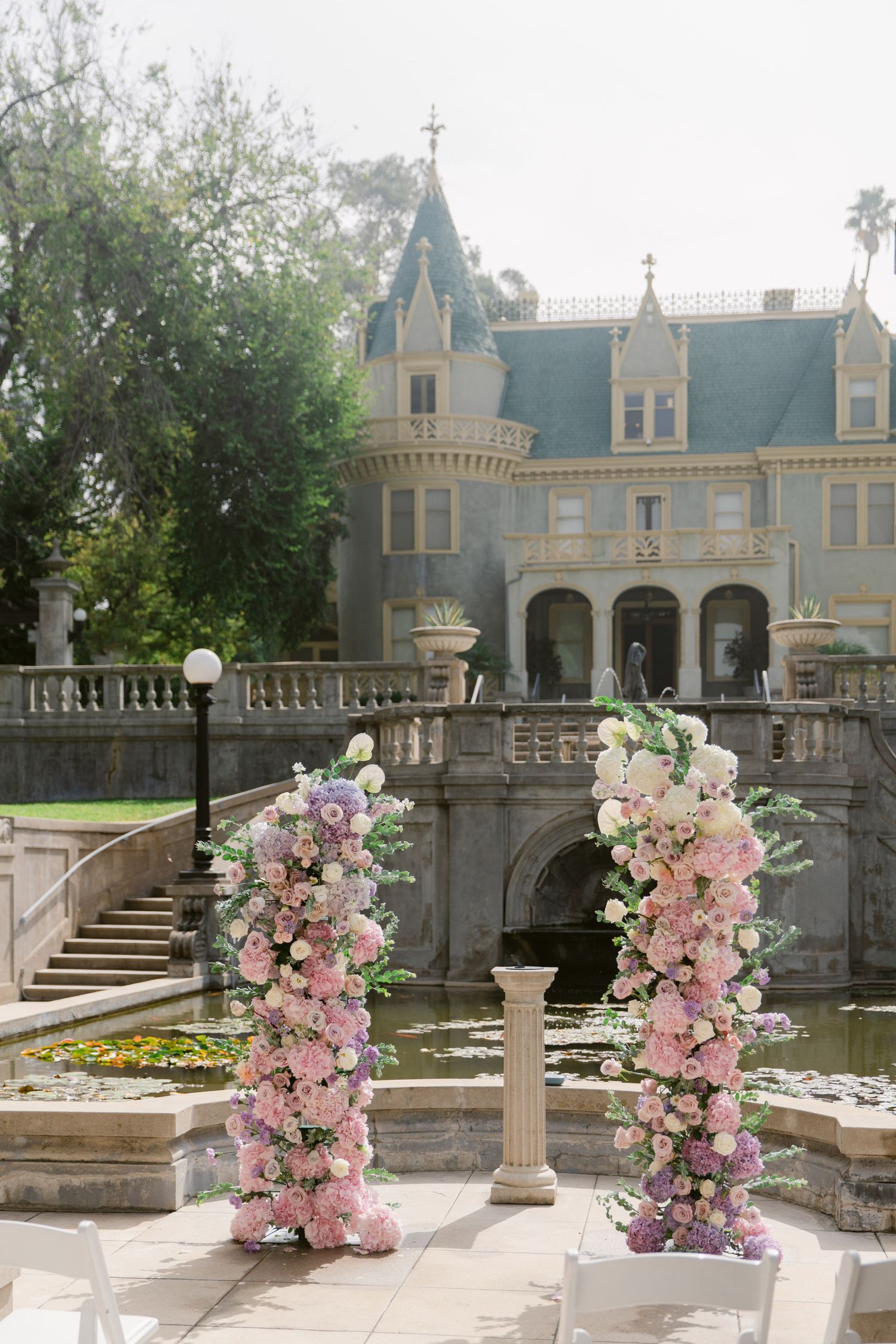 Ornate castle-like venue with pink floral arch decorations and stone columns.
