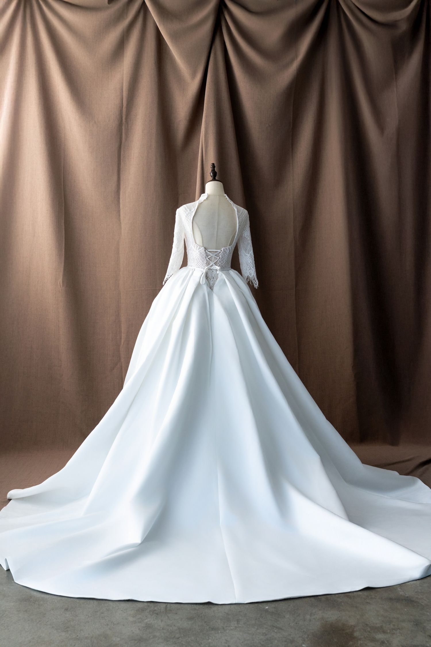 Elegant white satin wedding gown with dramatic cathedral train displayed from behind.