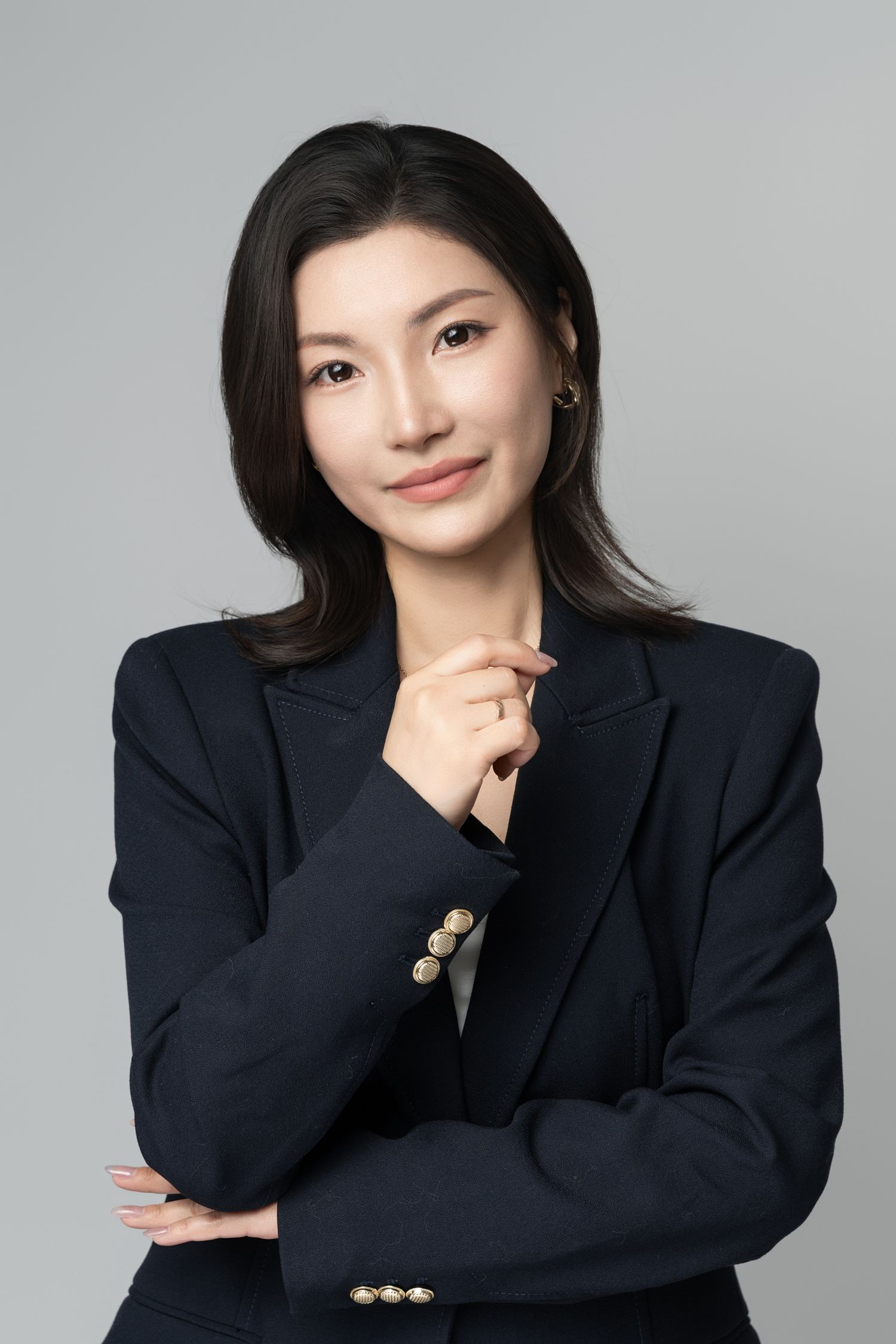Professional studio portraits showing different poses in dark blazer against gray backdrop.